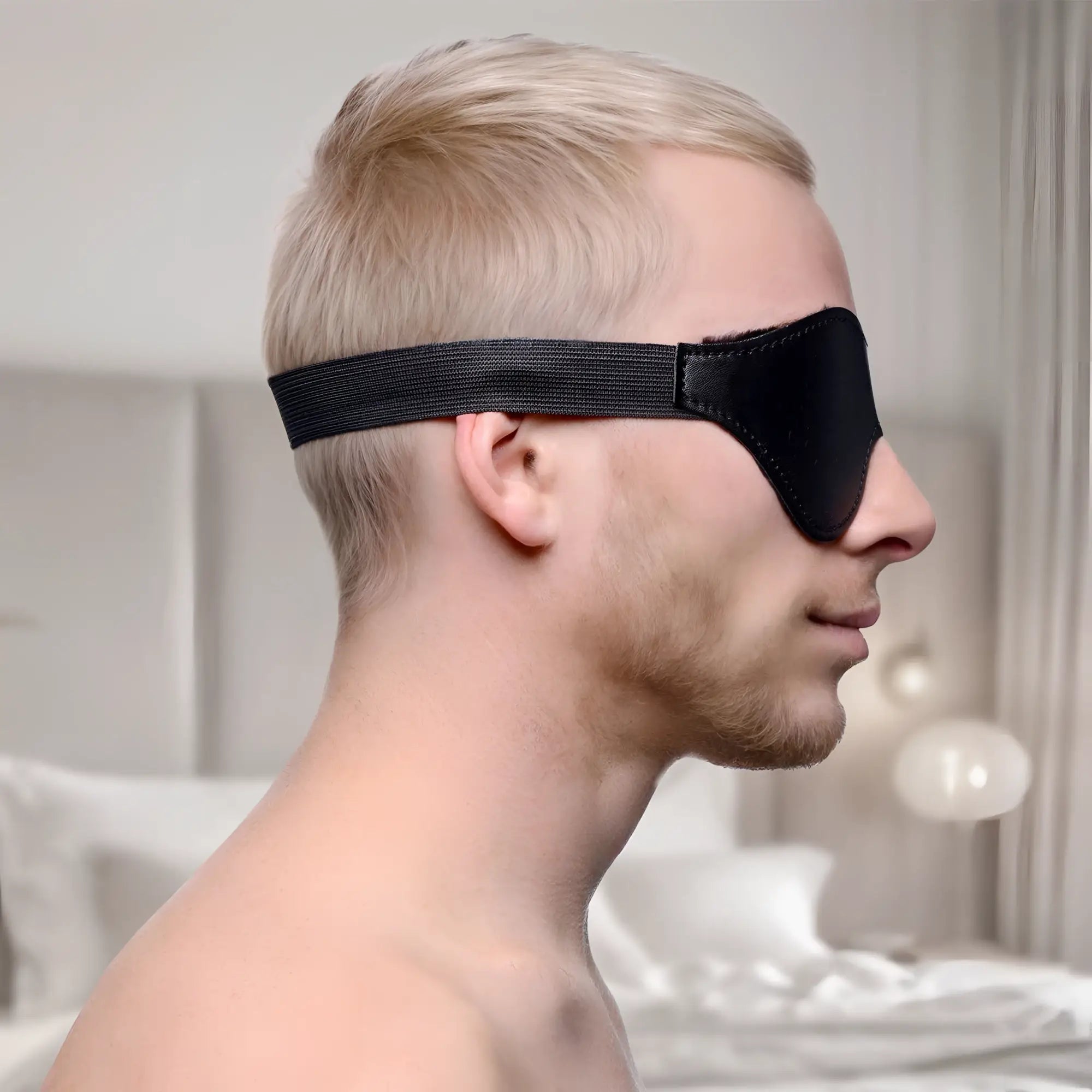 Strict Black Fleece Lined Blindfold: Profile view of a man wearing a smooth black blindfold with an elastic strap.