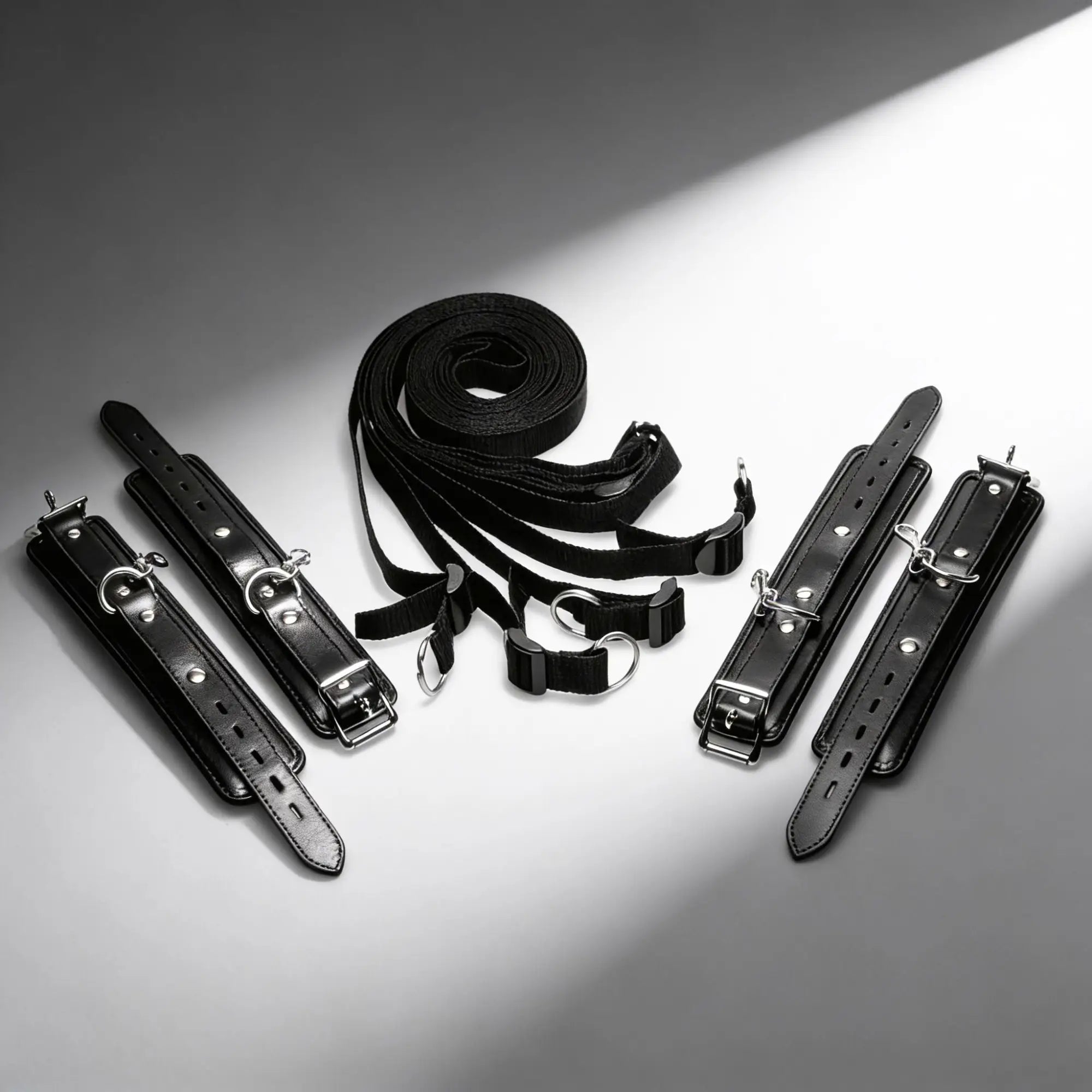 Strict Deluxe Bed Restraint System: Black leather-style cuffs and adjustable nylon straps with silver metal hardware.