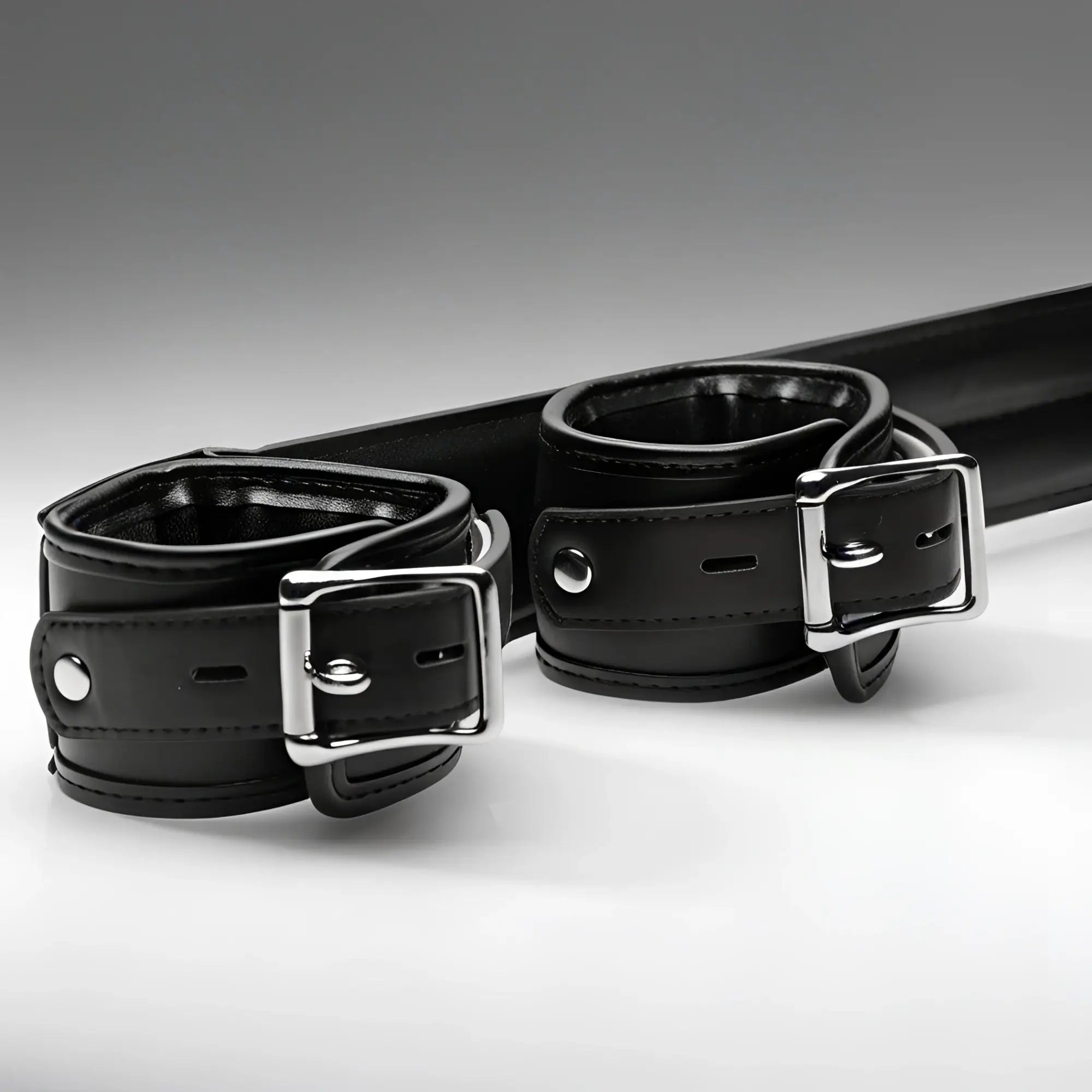 Strict Deluxe Spreader Bar: Black leather cuffs with silver metal buckles on a padded horizontal bar.