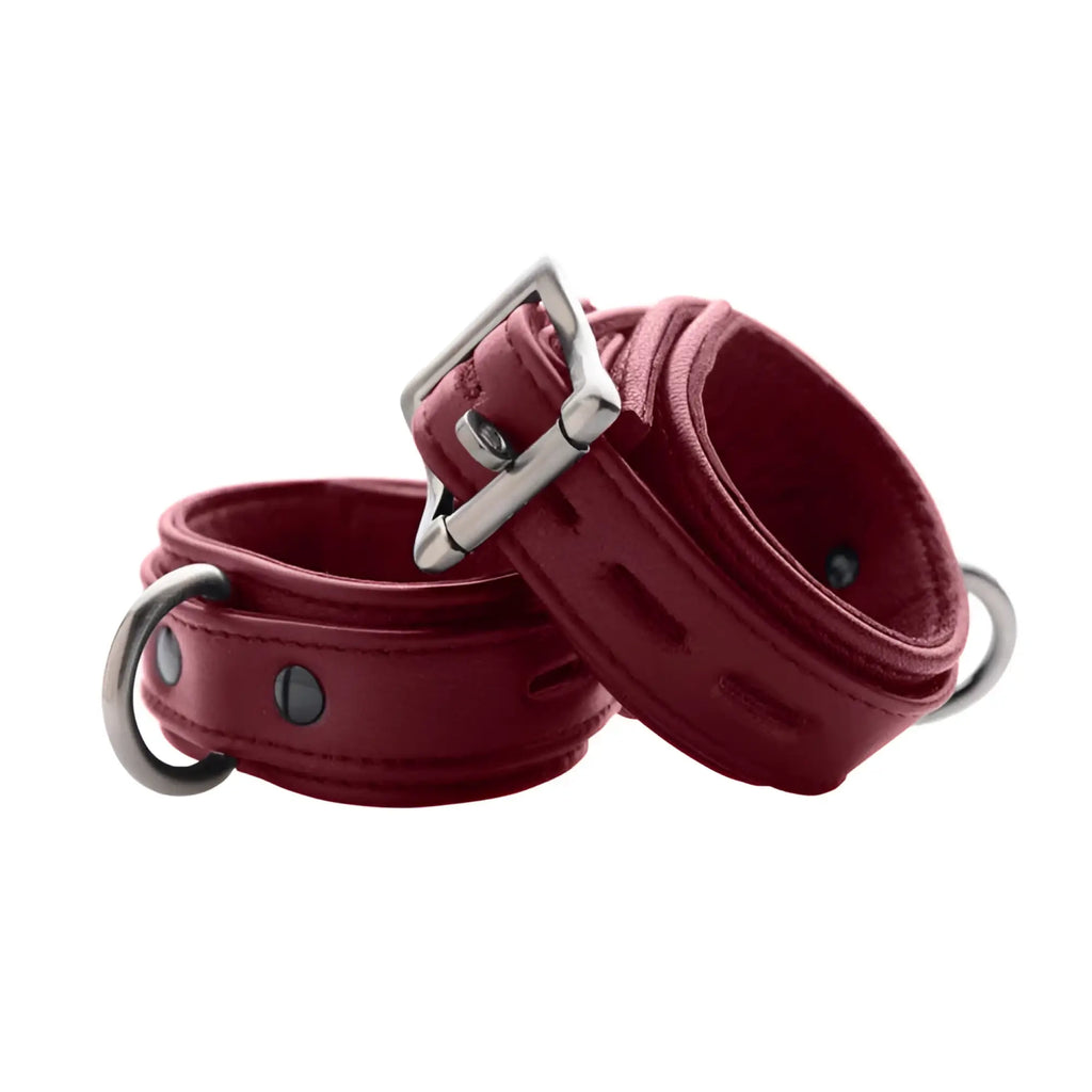 Strict Leather burgundy premium leather cuffs with silver-toned buckles and D-rings on a plain white background.