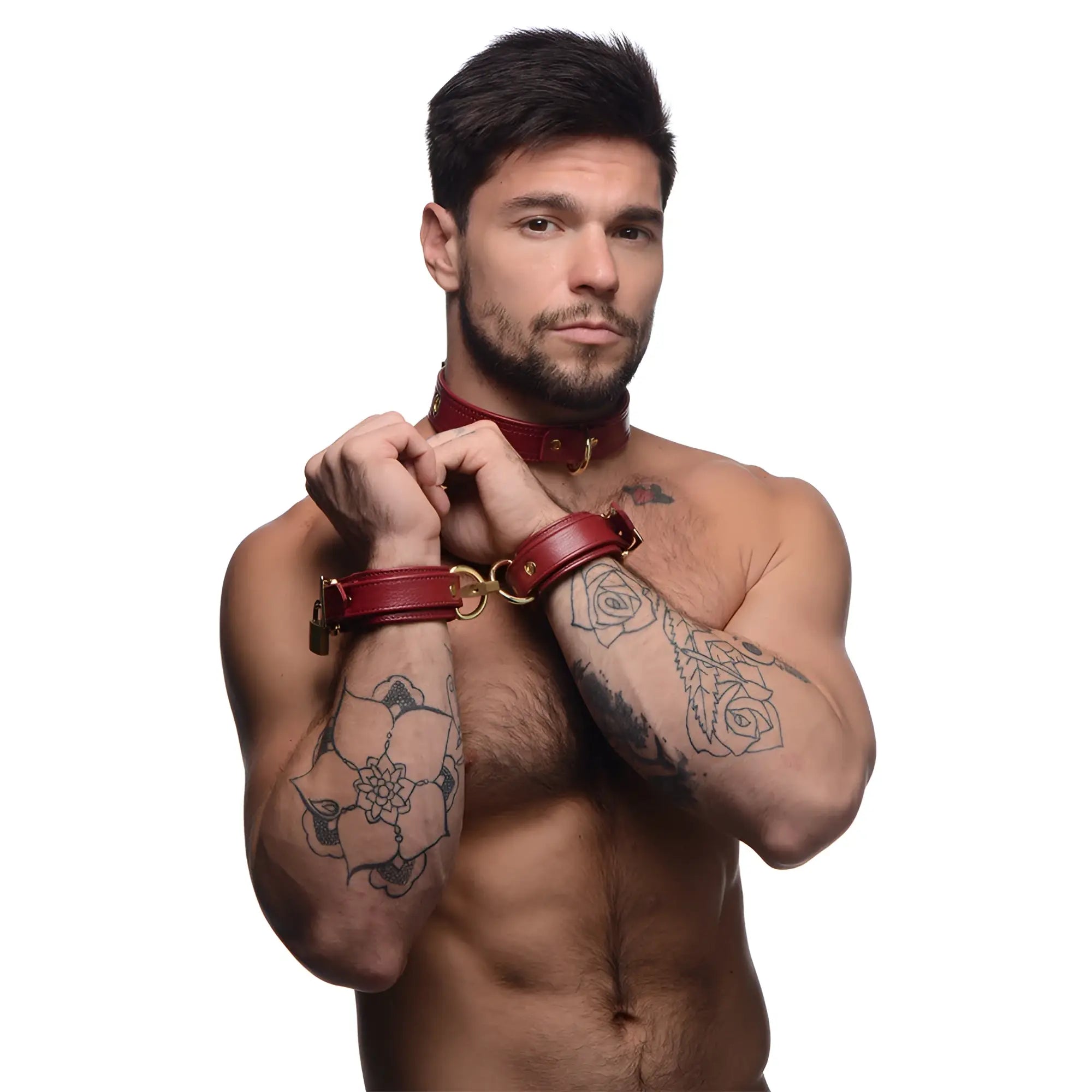 A shirtless man with tattoos wears a burgundy Strict Leather premium leather collar and locking wrist cuffs.