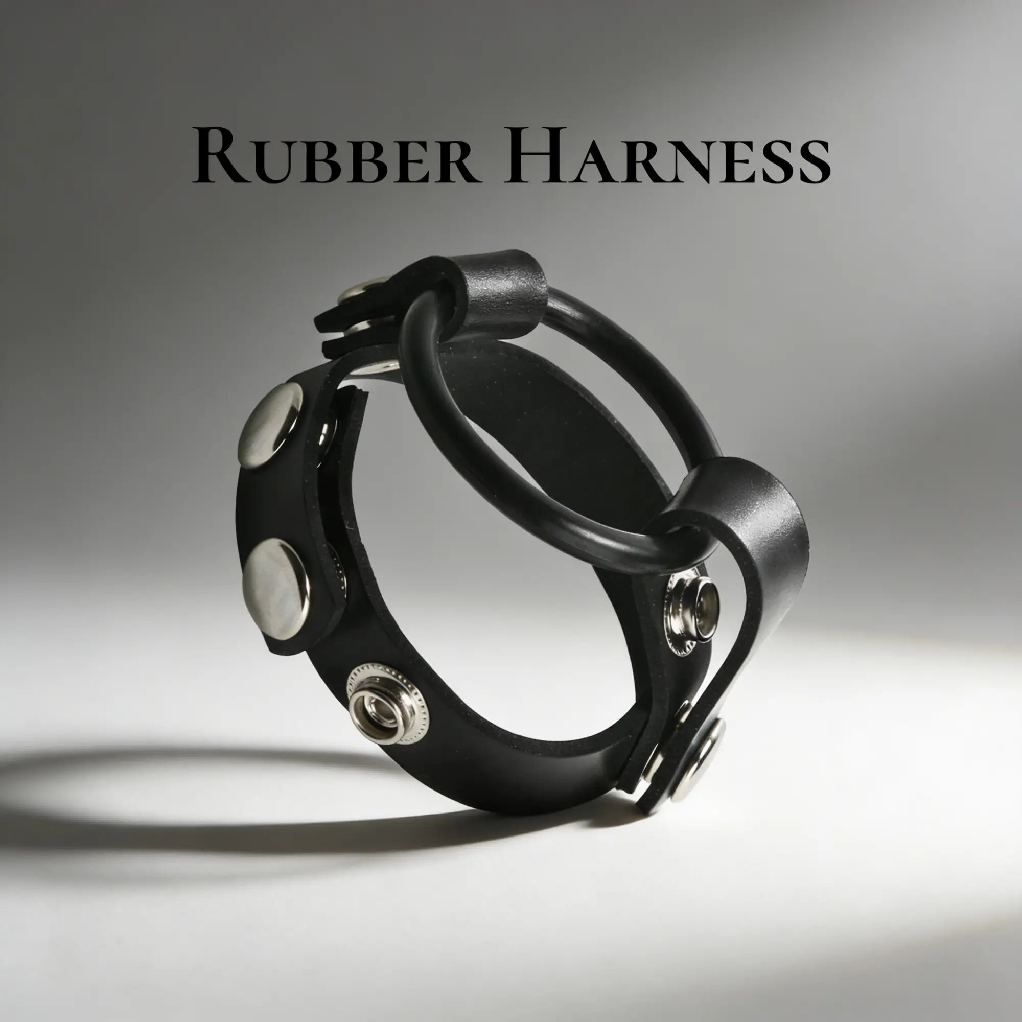 Black leather cock ring harness with metal snaps and a rubber ring.