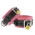 Strict Leather Deluxe locking restraints with pink textured leather, black straps, silver buckles, and gold padlocks.