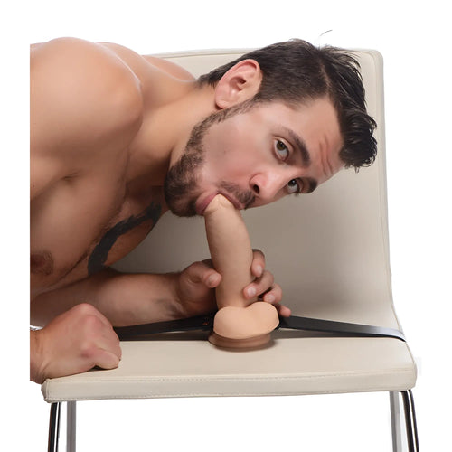 Strict Leather Leather Dildo Strap with a realistic-style dildo mounted on a black leather harness on a chair.