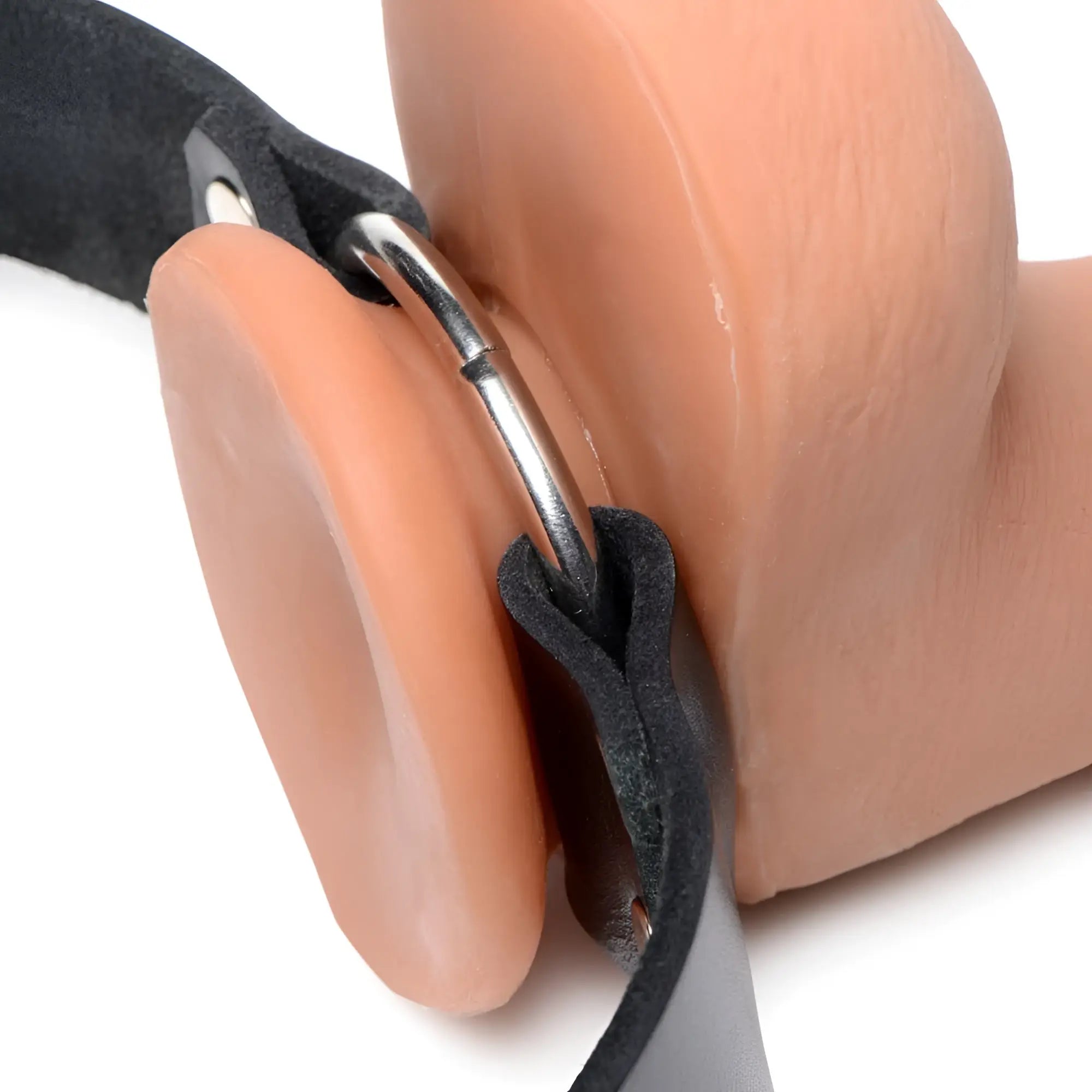 Strict Leather strap with a nude-colored dildo attached to a silver metal ring by black leather loops.