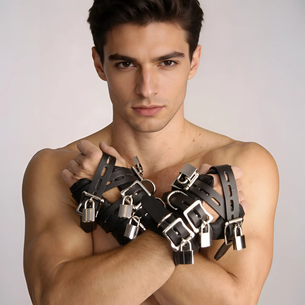 A shirtless man wears black leather Strict Leather four-buckle suspension cuffs with silver metal buckles and padlocks.