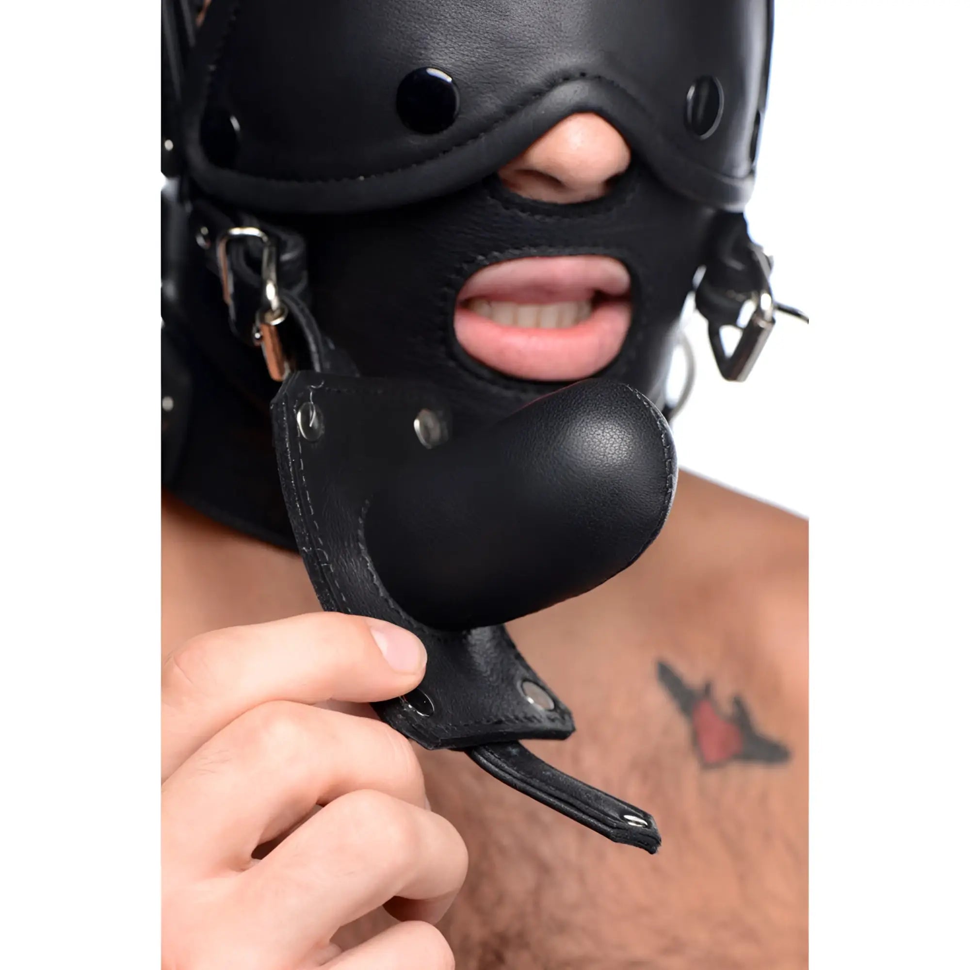 Strict Leather head harness in black leather, featuring a removable gag being held by a hand.