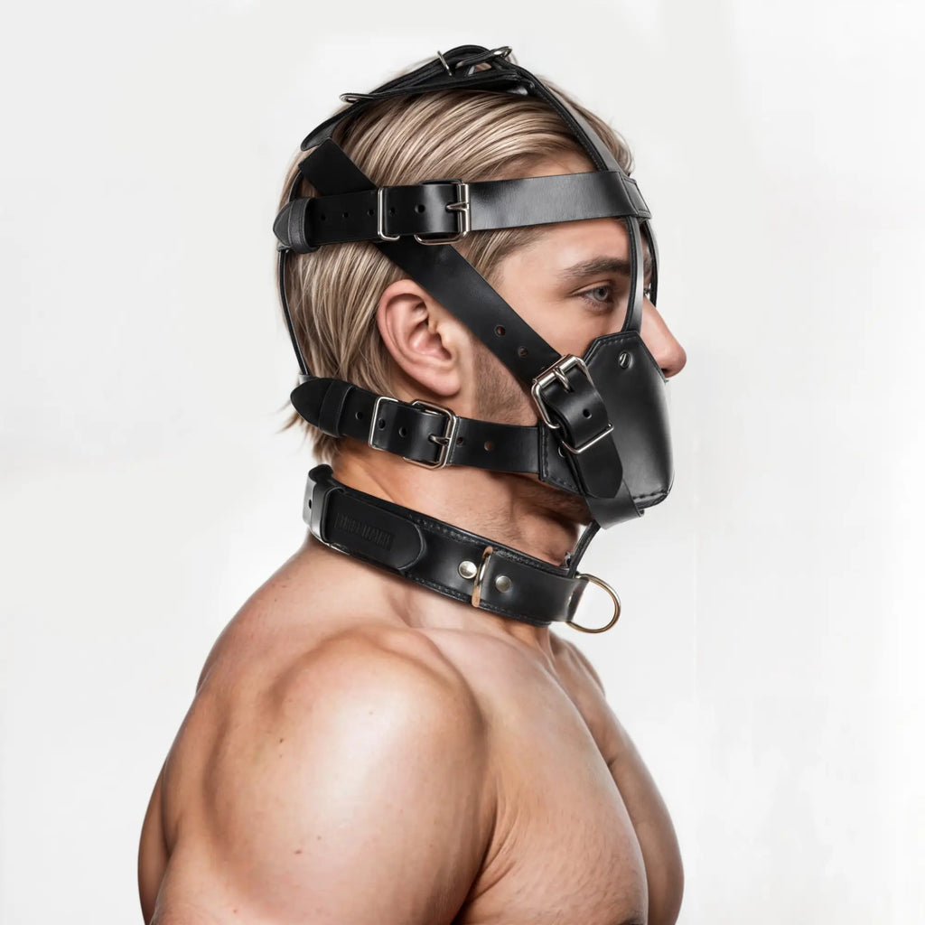 Side profile of a man wearing a black leather Strict Leather muzzle and matching collar with buckled straps.