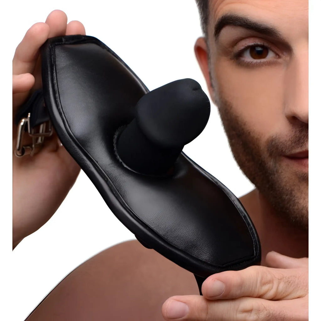 Strict Leather black padded leather mouth gag with a phallic-shaped silicone insert, held by a man.