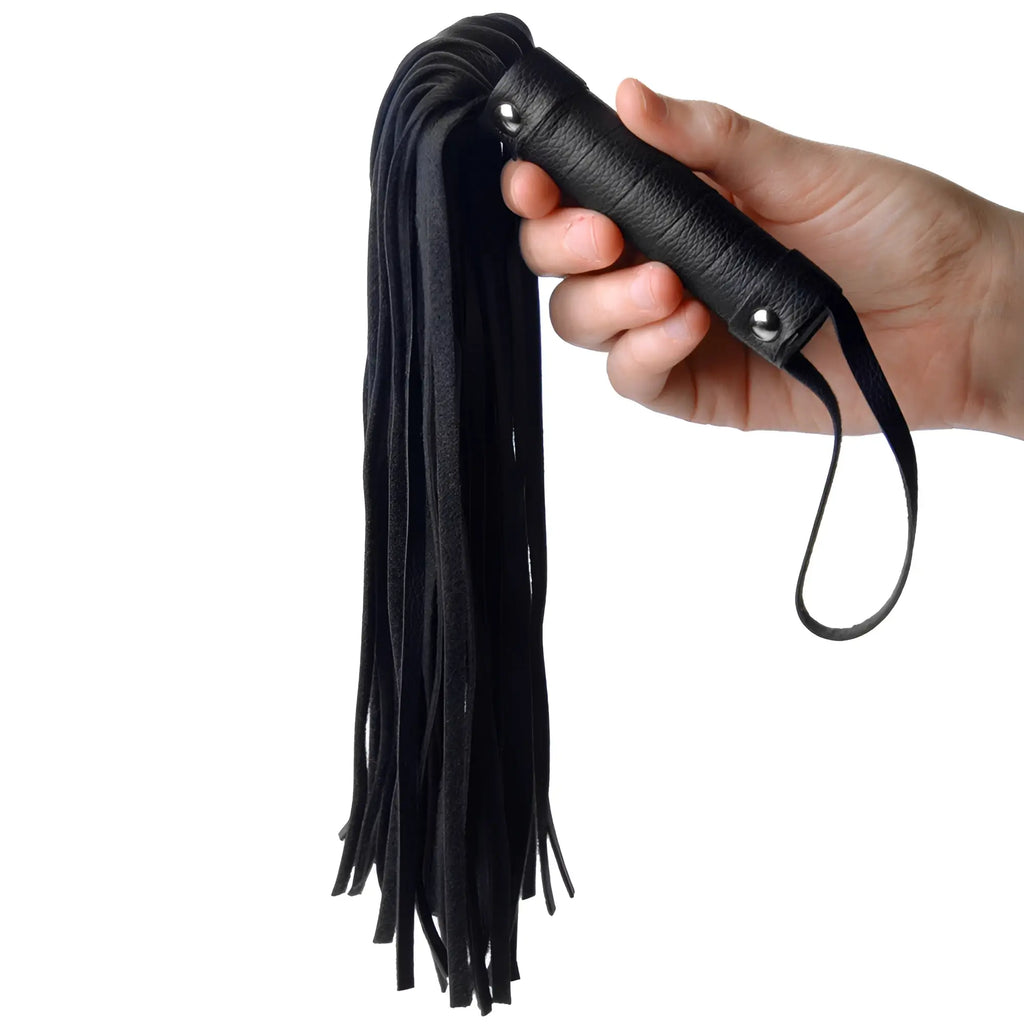 Strict Leather Pleather Pleasure Mini-Flogger: A hand holds a black mini-flogger with a wrist strap on white background.