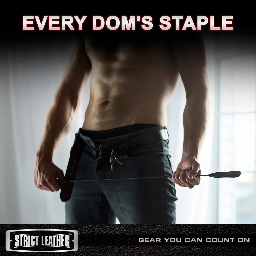 Strict Leather short black riding crop held horizontally by a shirtless man in jeans. Text reads: Every Dom's Staple.