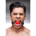 Strict Leather silicone ball gag with black leather straps worn by a man against a grey background.