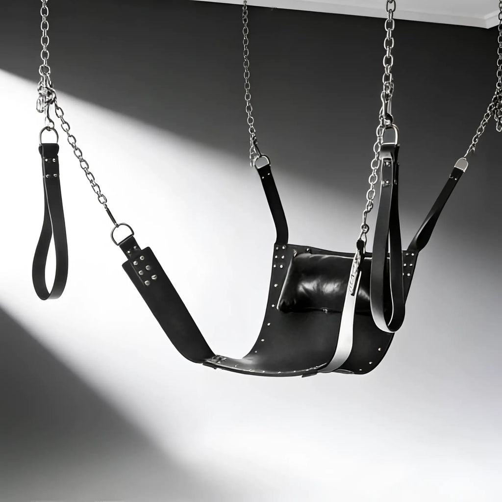 Strict Leather sling in black leather with metal chains, stirrups, and an attached head pillow.