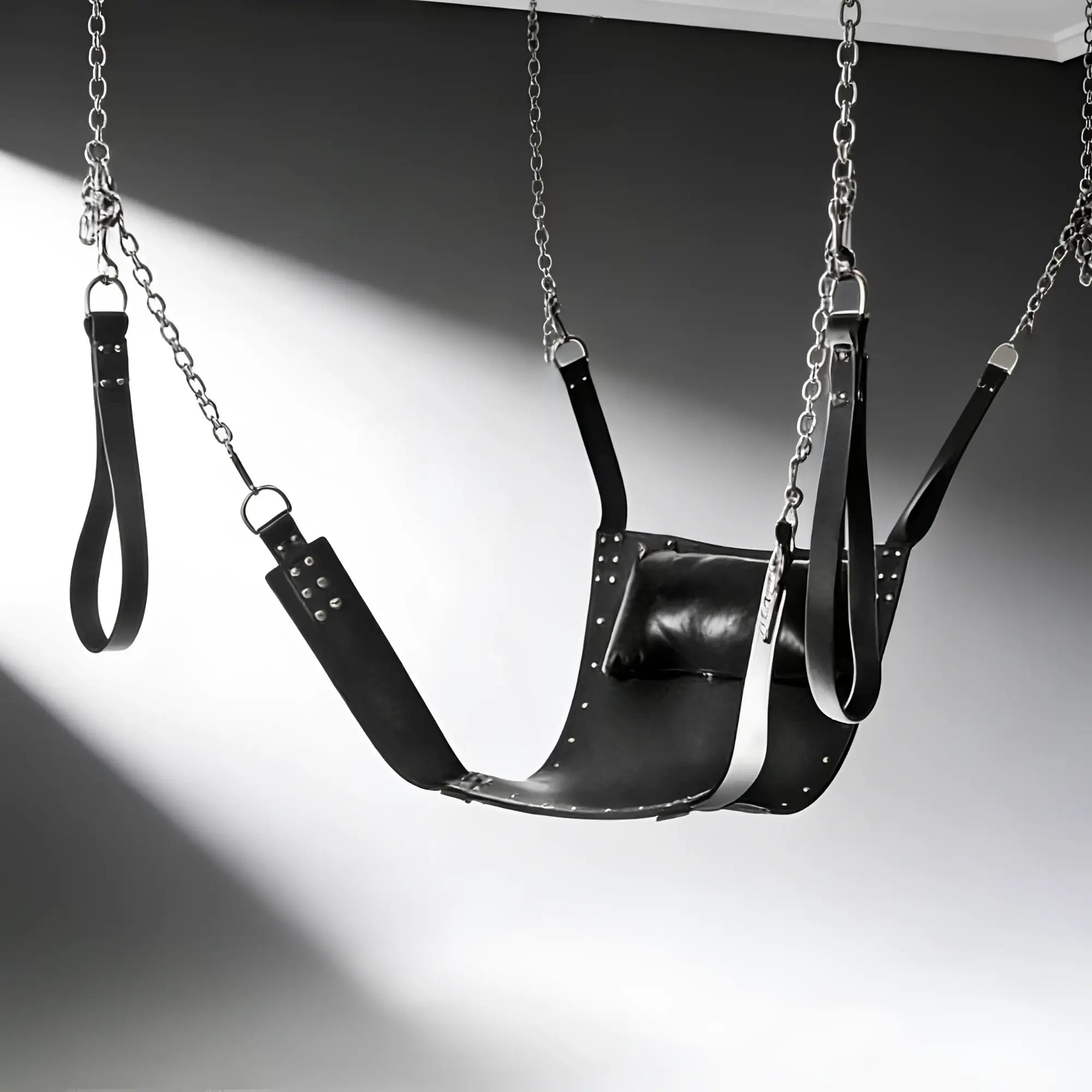 Strict Leather sling in black leather with metal chains, stirrups, and an attached head pillow.