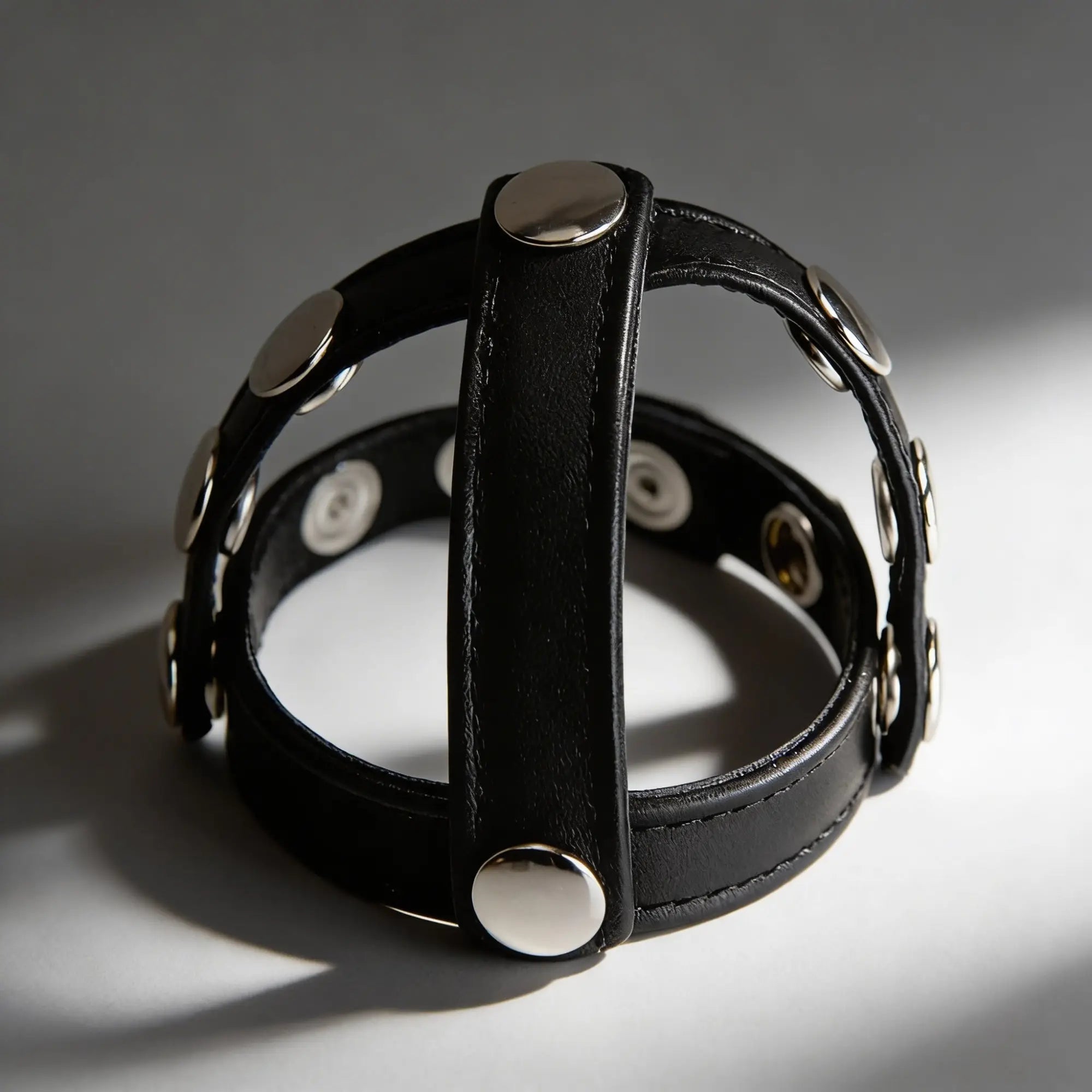 Strict Leather cock and ball harness in black leather with silver snap buttons, featuring a circular, adjustable design.
