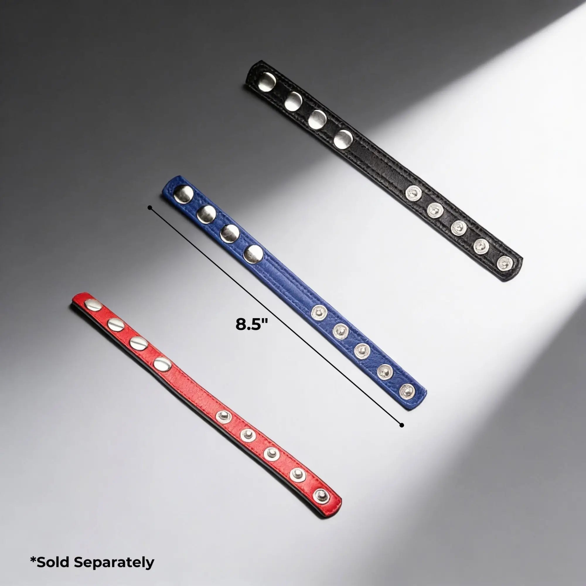 Three Strict Leather cock rings in red, blue, and black with silver snaps, one measuring 8.5 inches.