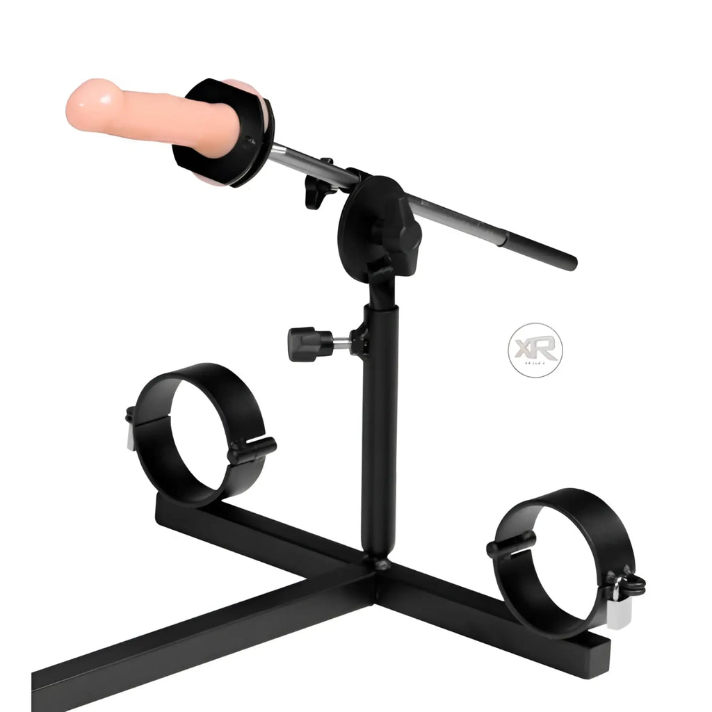 Strict Leather Stockade with black metal frame, ankle cuffs, adjustable rod, and flesh-toned attachment.