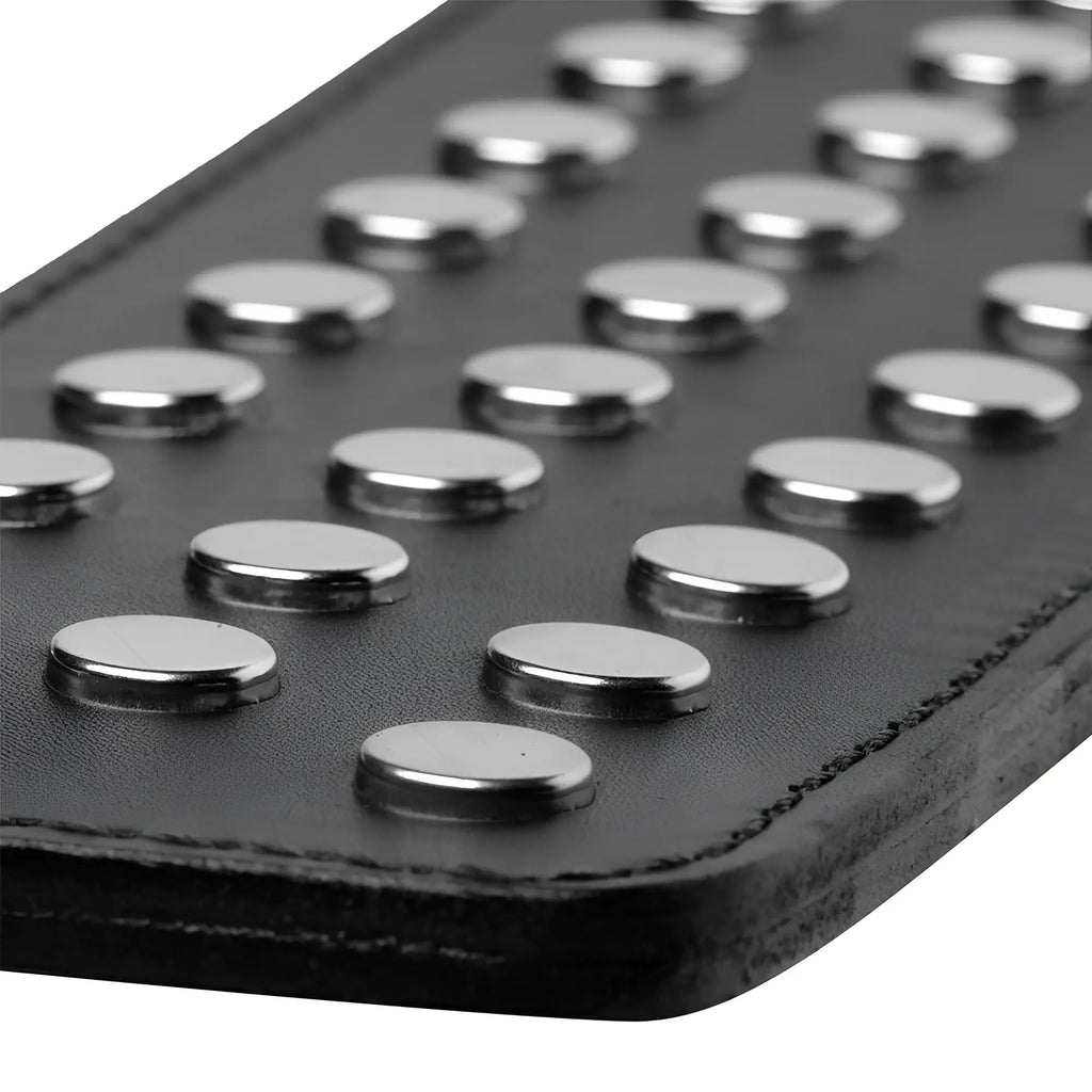 Close-up of a black Strict Leather studded paddle featuring two rows of polished silver metal studs on leather.