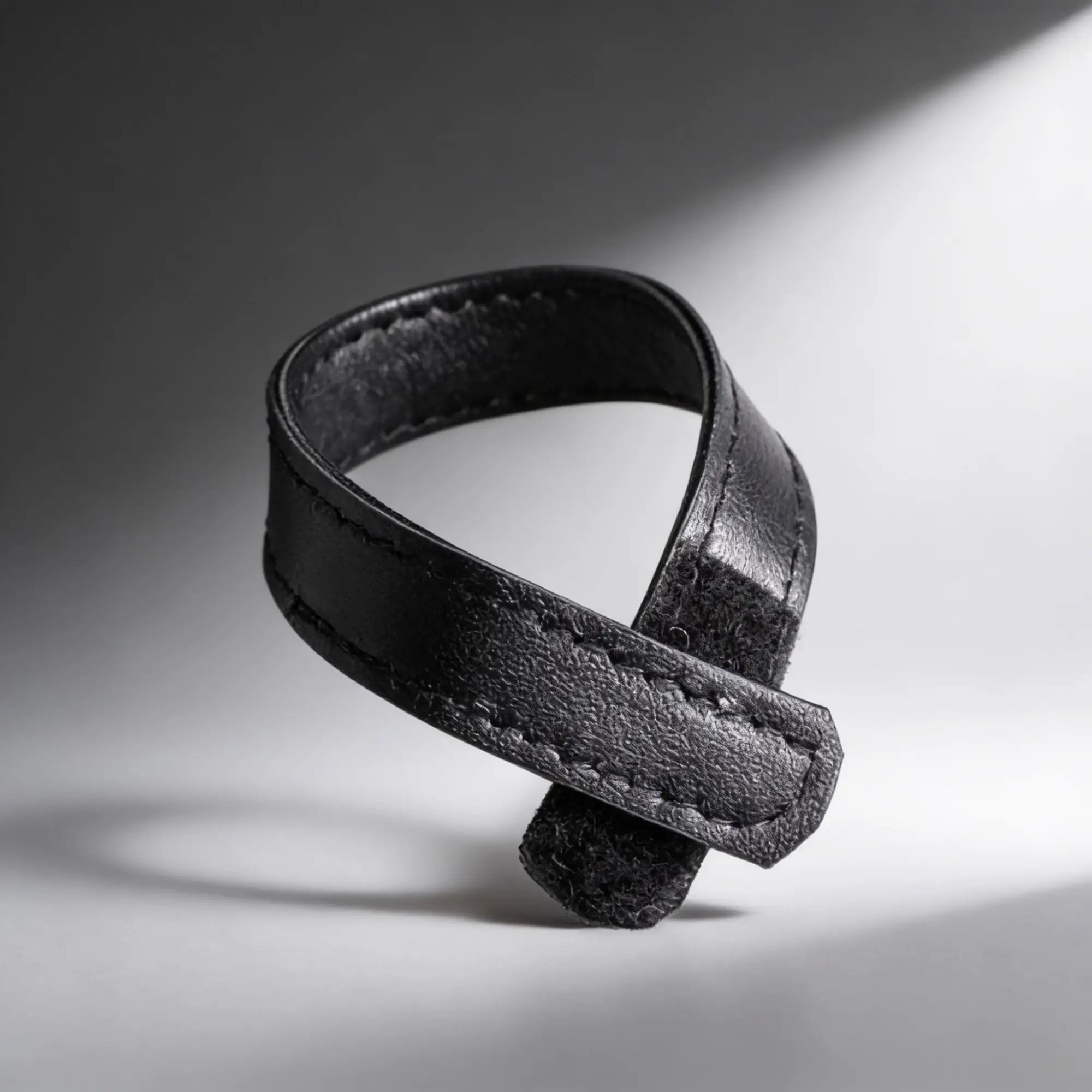 Black leather and velcro cock ring, with a textured finish and stitched detailing.