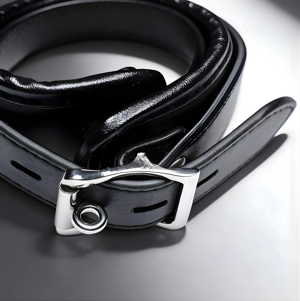 Strict Padded Thigh Sling with Wrist Cuffs: A coiled black leather strap with silver buckle and metal O-ring.