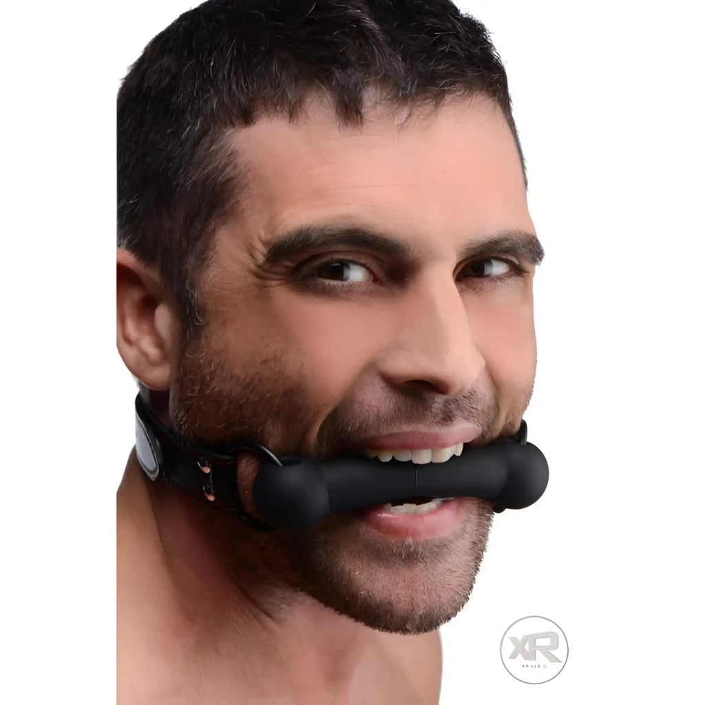 A man wearing a black leather Strict Silicone Bit Gag with a smooth, black cylindrical mouthpiece.