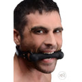 A man wearing a black leather Strict Silicone Bit Gag with a smooth, black cylindrical mouthpiece.