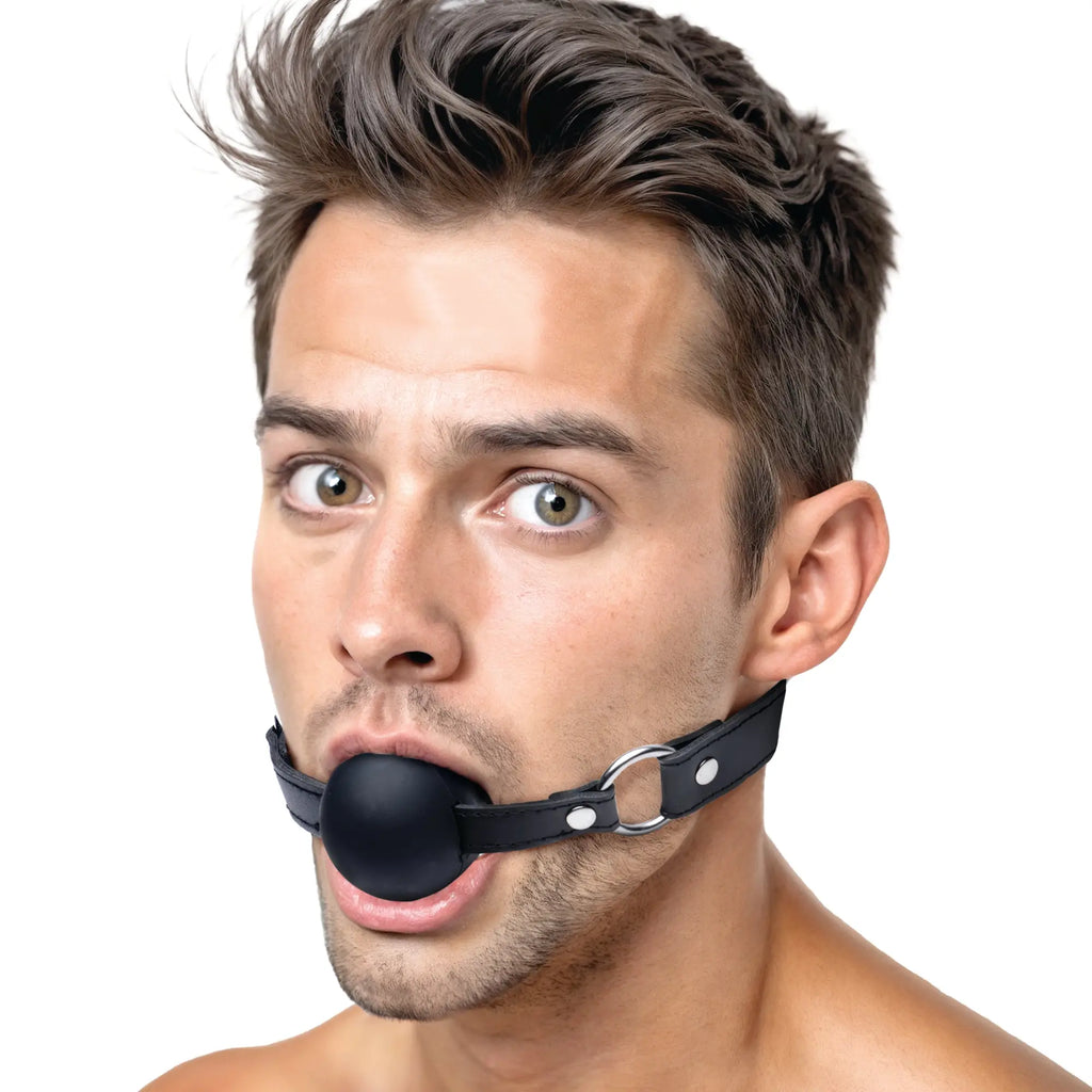 Man wearing a black Strict XL silicone ball gag with a matching black leather-style strap and silver metal hardware.