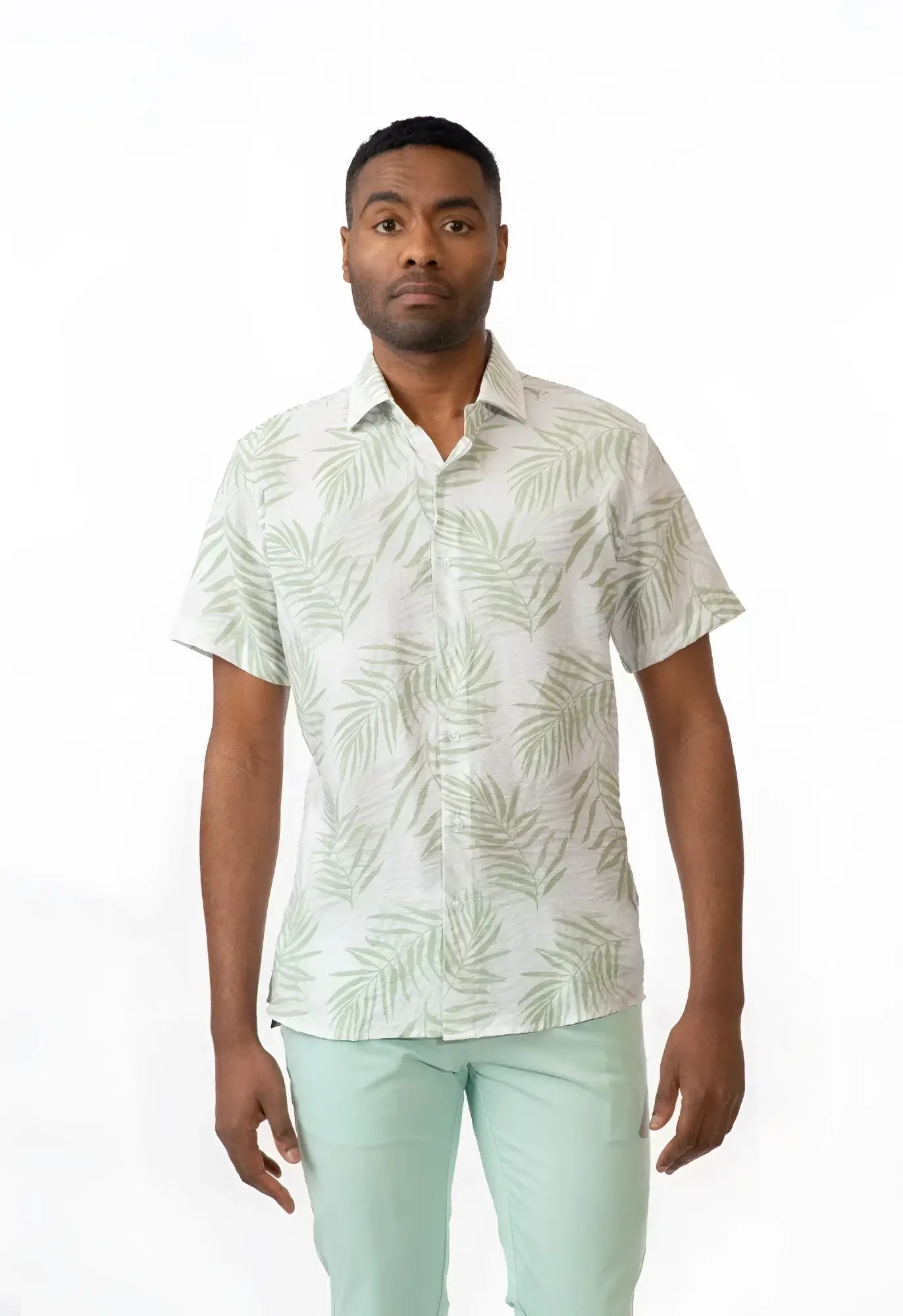 A man wearing a summer rain short-sleeved shirt with light green palm leaf pattern on an off-white background
