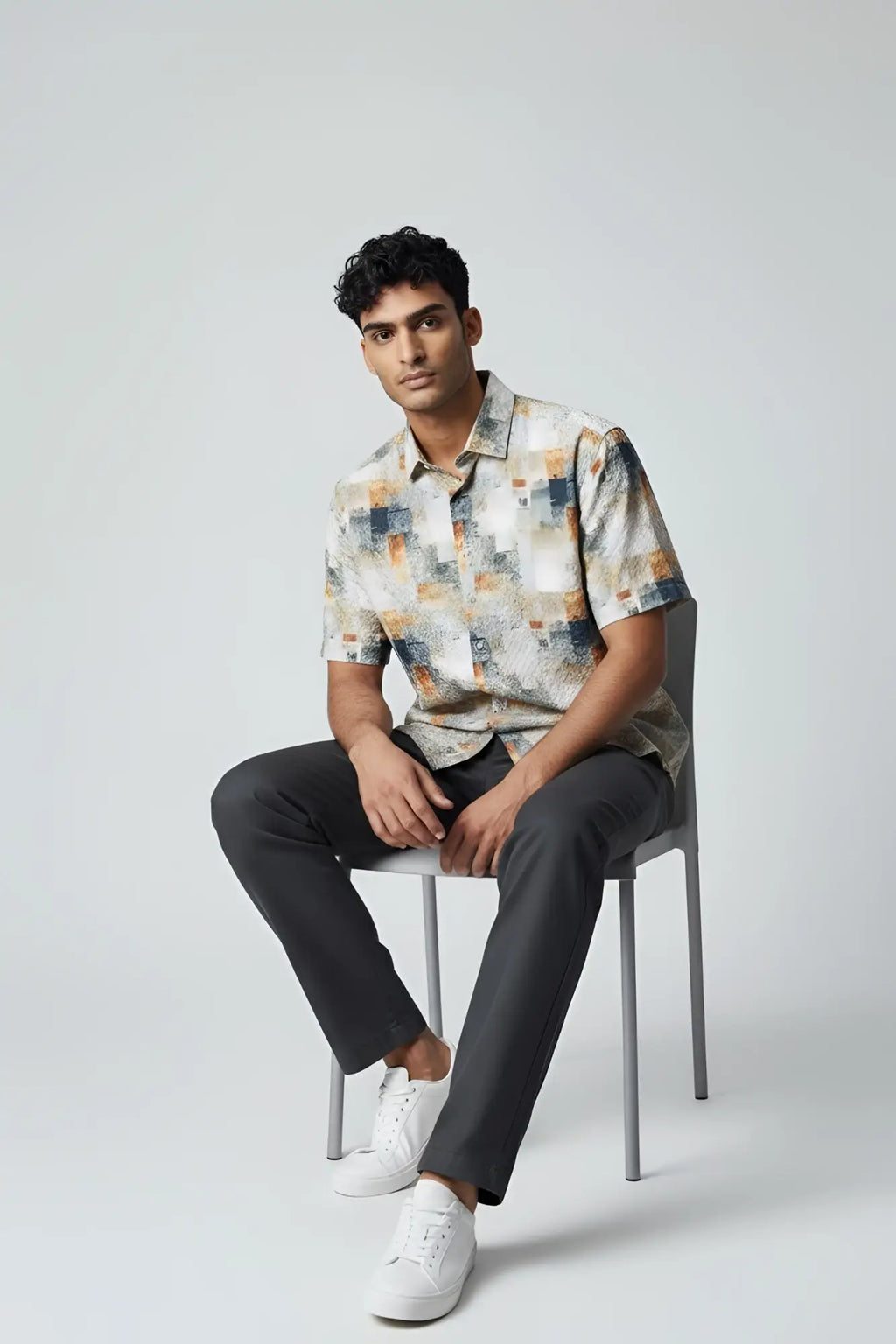 A man wearing a suslo crinkled fabric short-sleeved shirt with an abstract geometric pattern in beige gray and orange