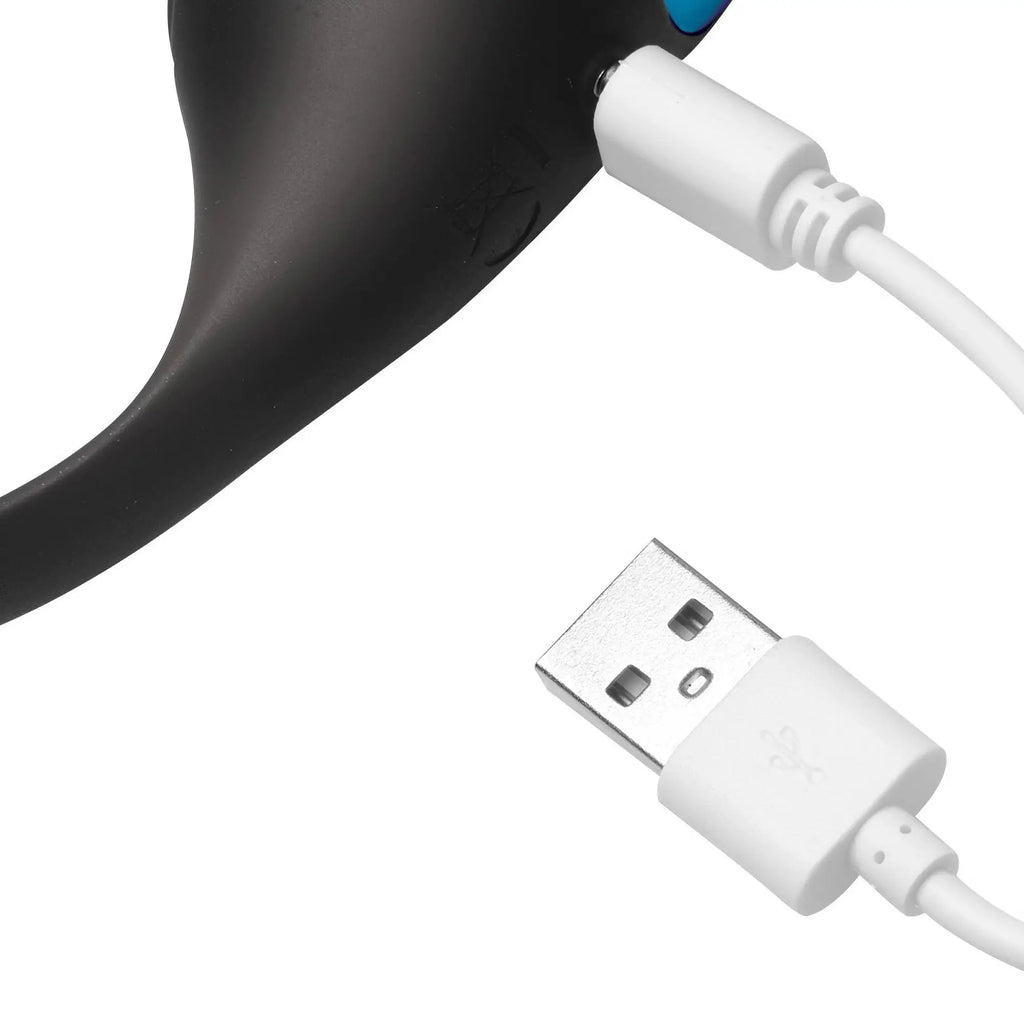 Swell 10X black prostate plug with a white USB charging cable connected to the device.