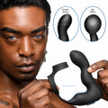 A person holds a matte black Swell 10X inflatable prostate plug with an integrated cock ring and taint stimulator.