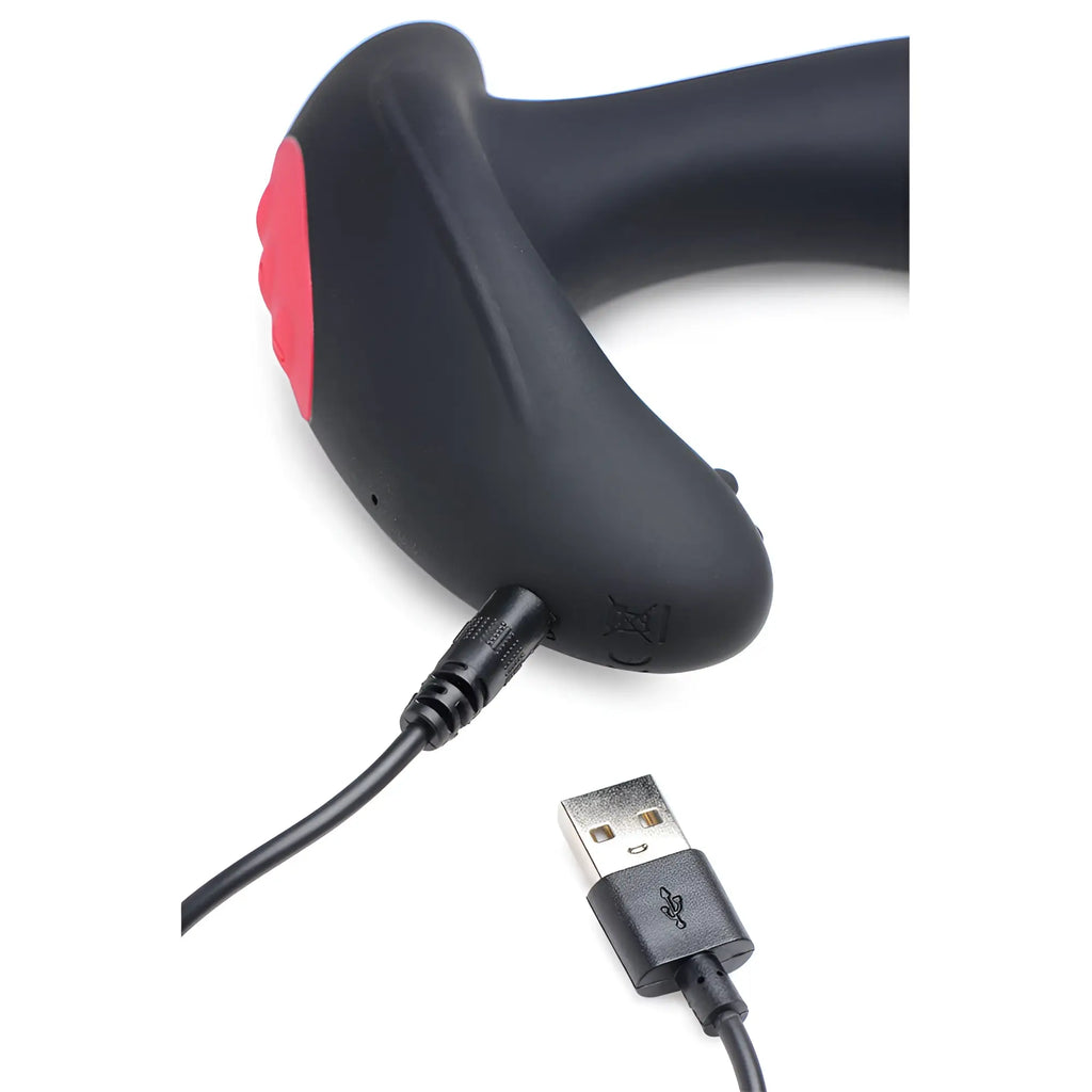 Black Swell 10X inflatable silicone prostate plug with pink accents, shown charging via a USB cable on a white background.