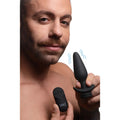 Man holding a black Tailz interchangeable vibrating silicone anal plug and remote controller.