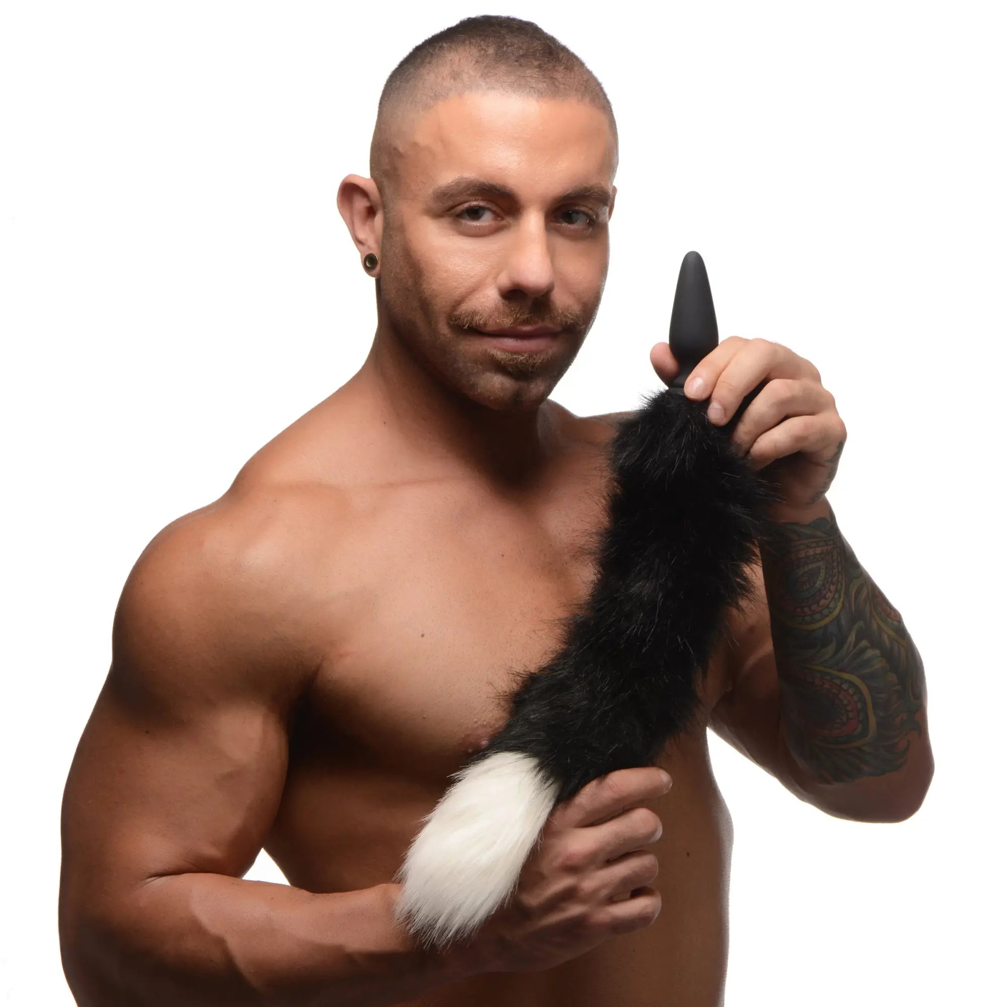 A man holds a black Tailz small anal plug attached to a black-and-white fluffy faux-fur fox tail.