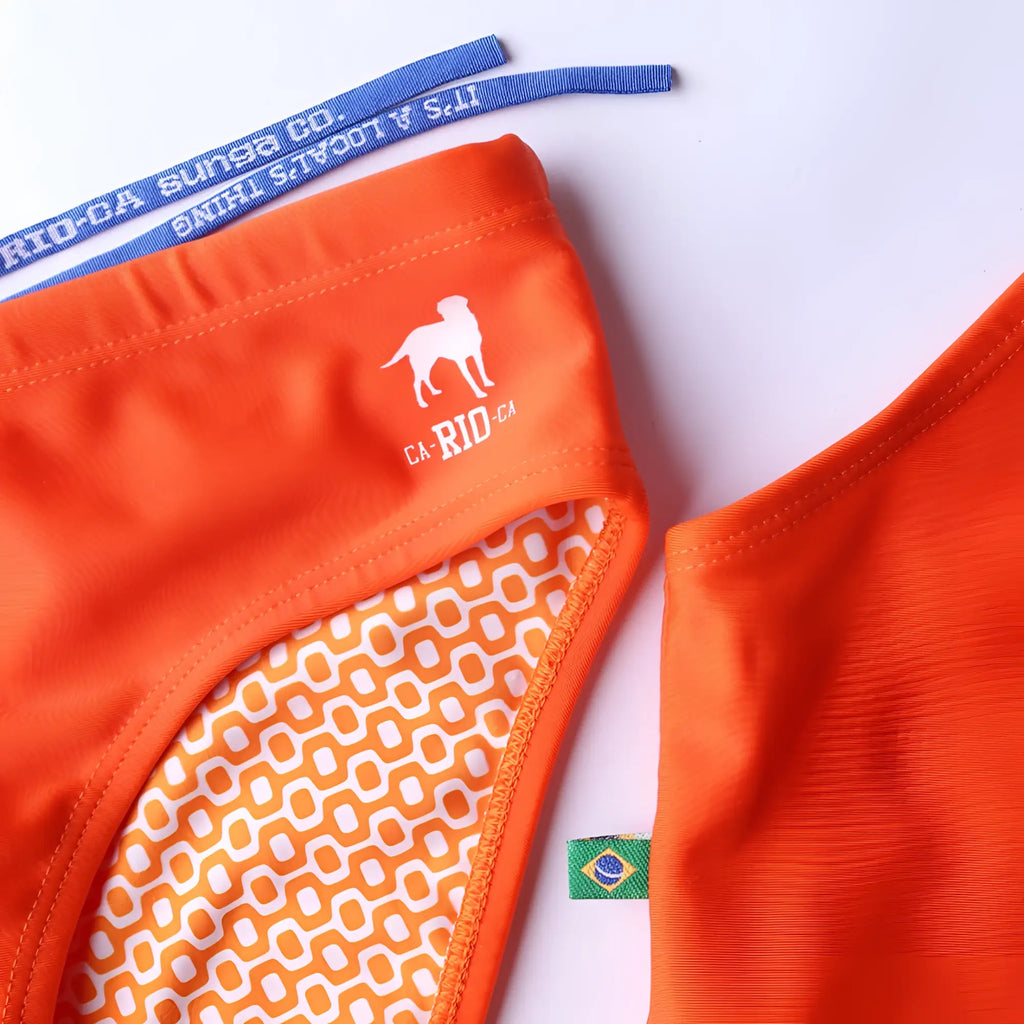 Bright orange tangerine solids men’s swimming sunga with white dog logo ca rio-ca text and geometric inner lining