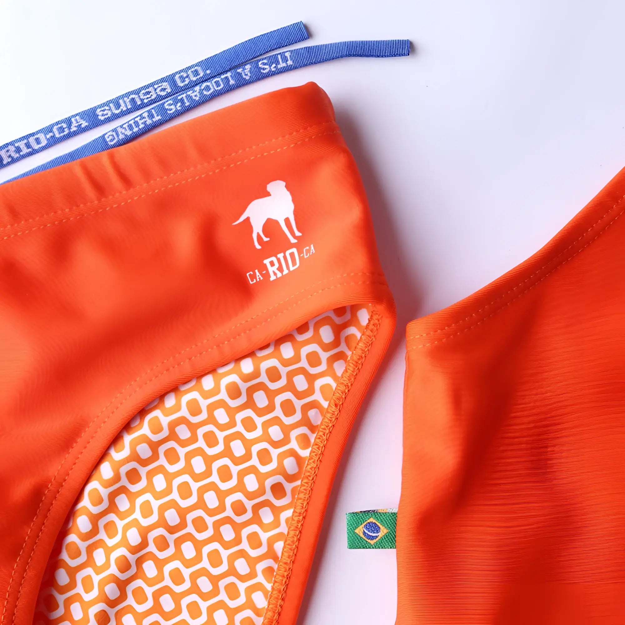 Bright orange tangerine solids men’s swimming sunga with white dog logo ca rio-ca text and geometric inner lining