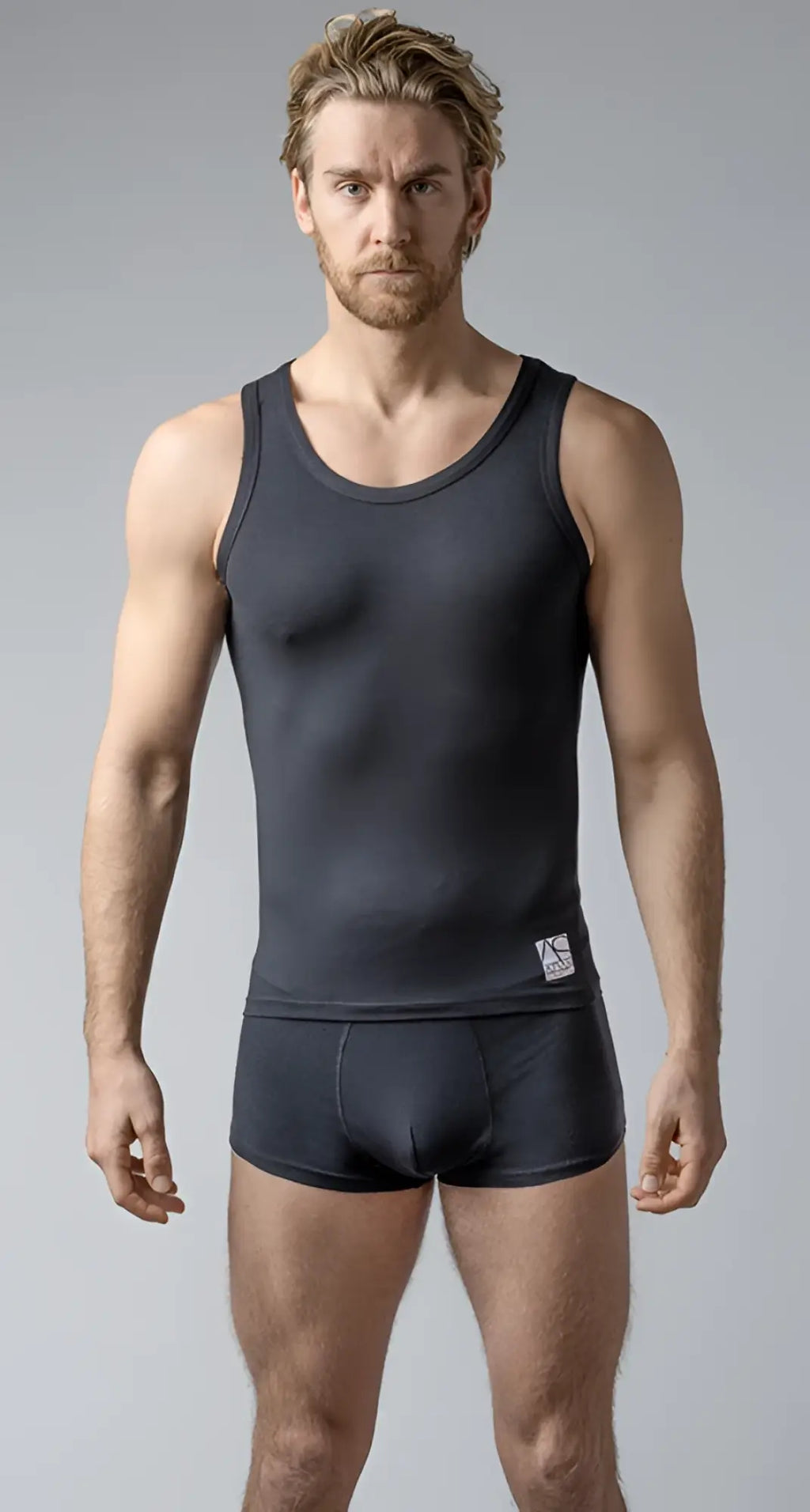 Black sleeveless tank with simple round neckline and subtle branding tag on lower left side