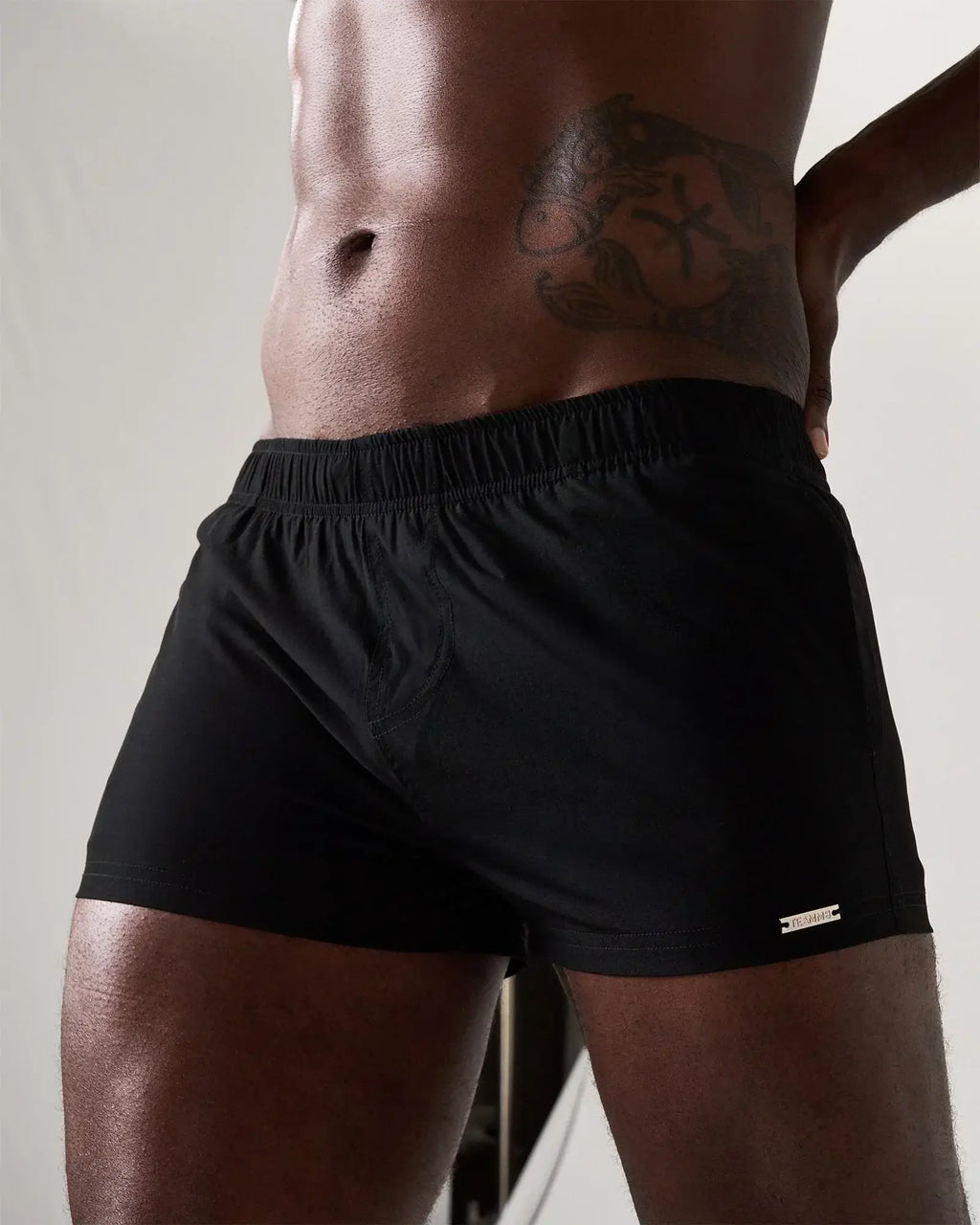 Black statement swim short with elastic waistband and small metallic logo on lower right leg for athletic use