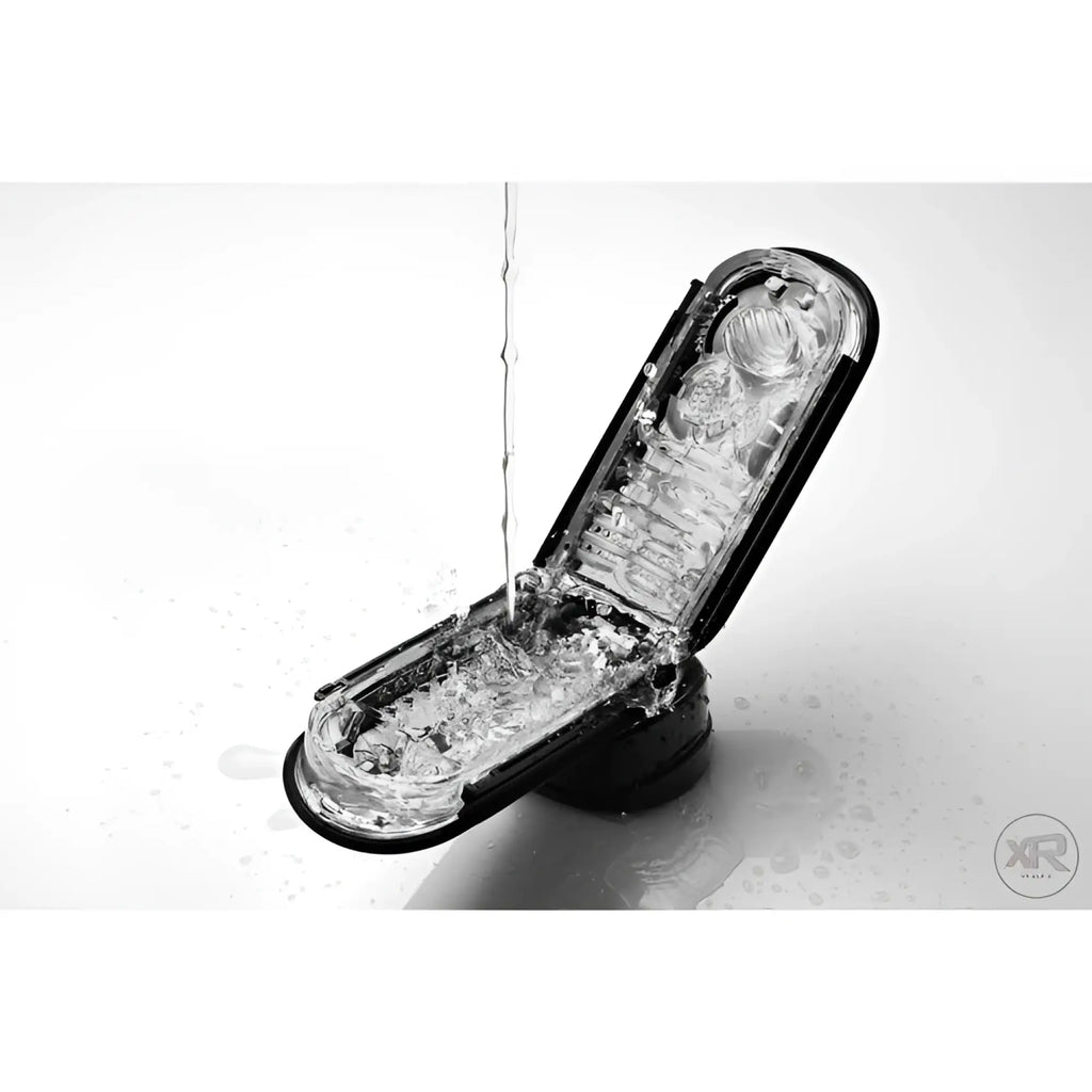 Tenga Flip 0-Zero Black open, showing its textured clear internal sleeve being rinsed with water against a white surface.