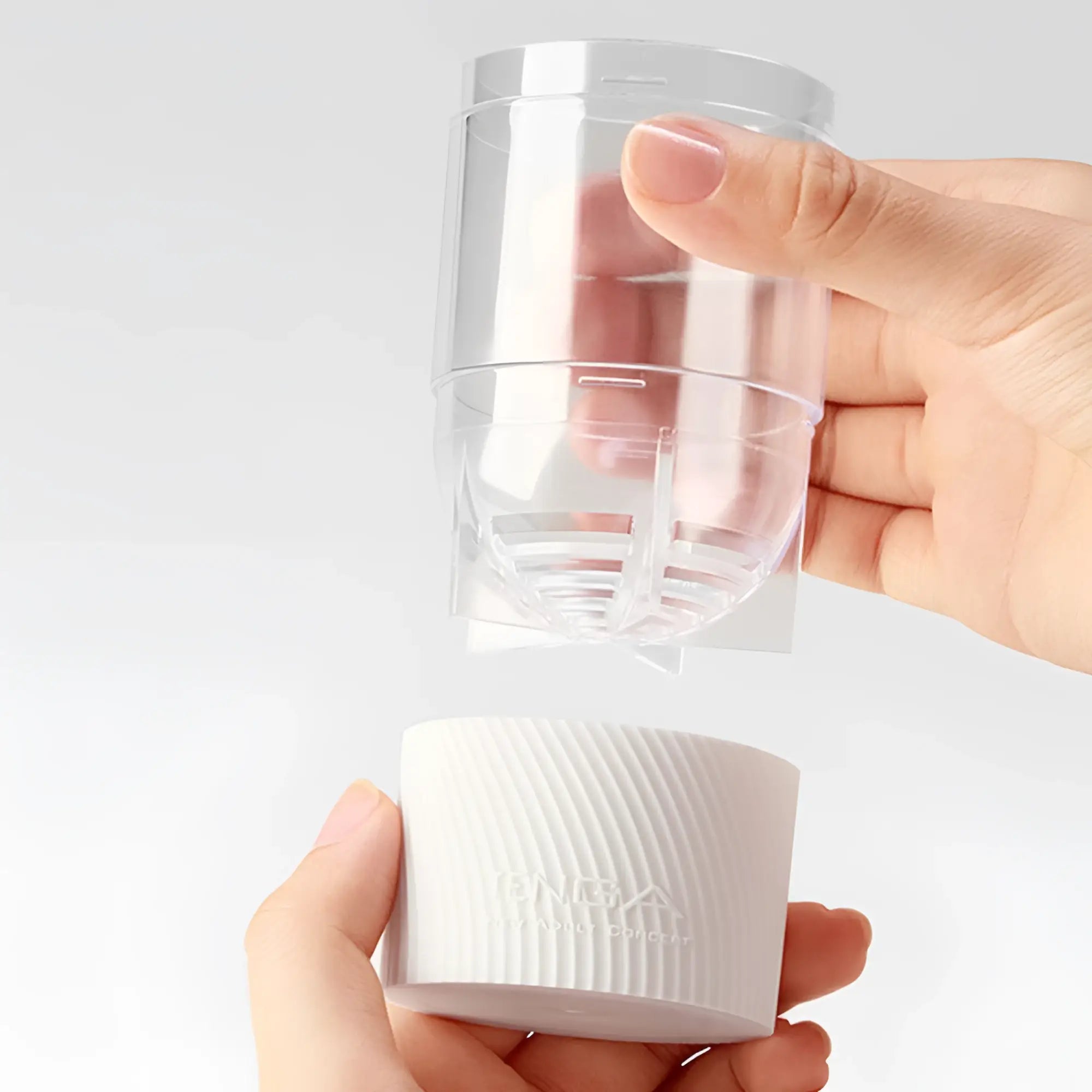 Hands assembling the white, textured Tenga Spinner 05 Beads stroker by inserting a clear plastic inner core.