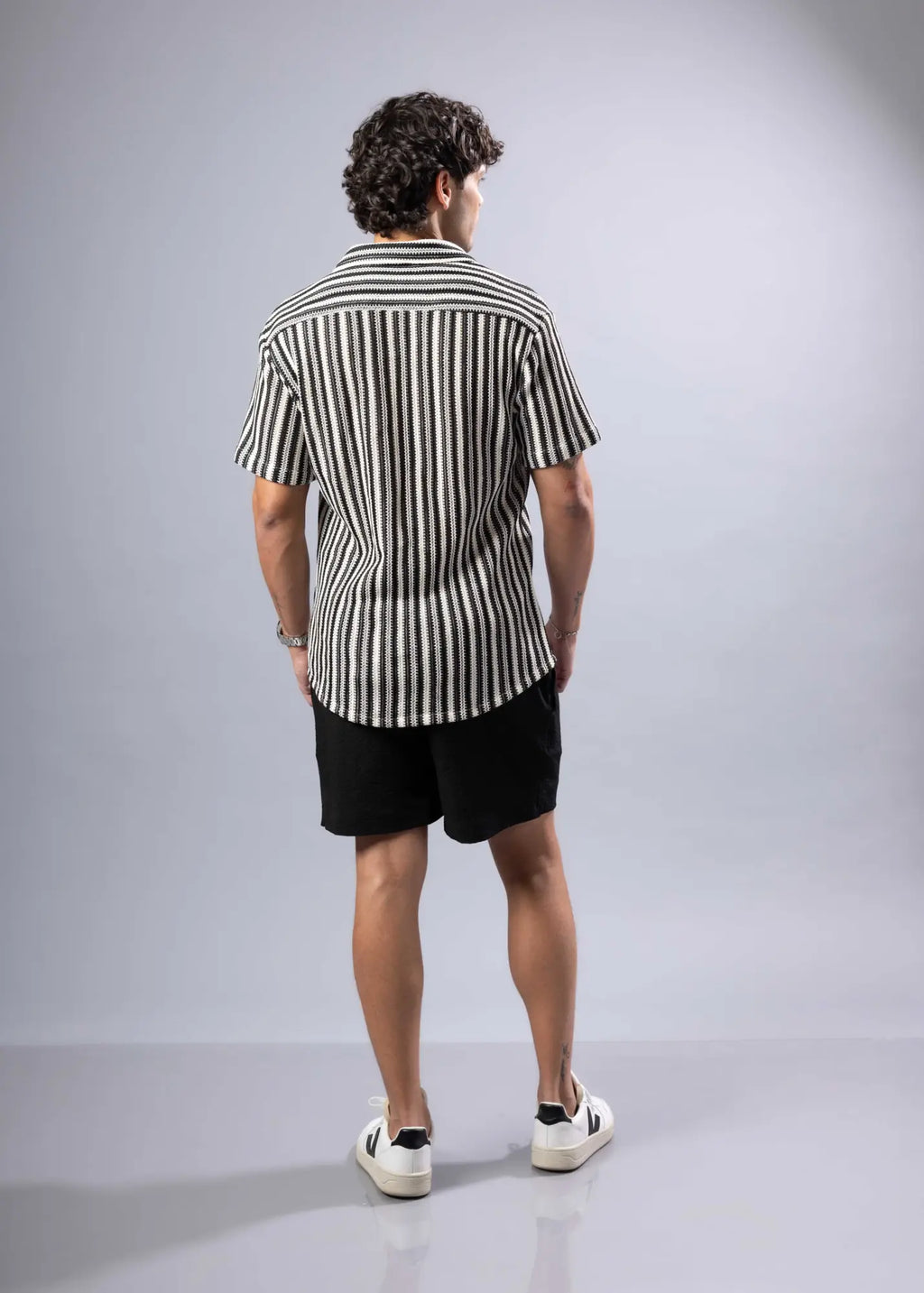 A man wearing a black and white vertically striped texture knit short-sleeved shirt in cotton blend fabric