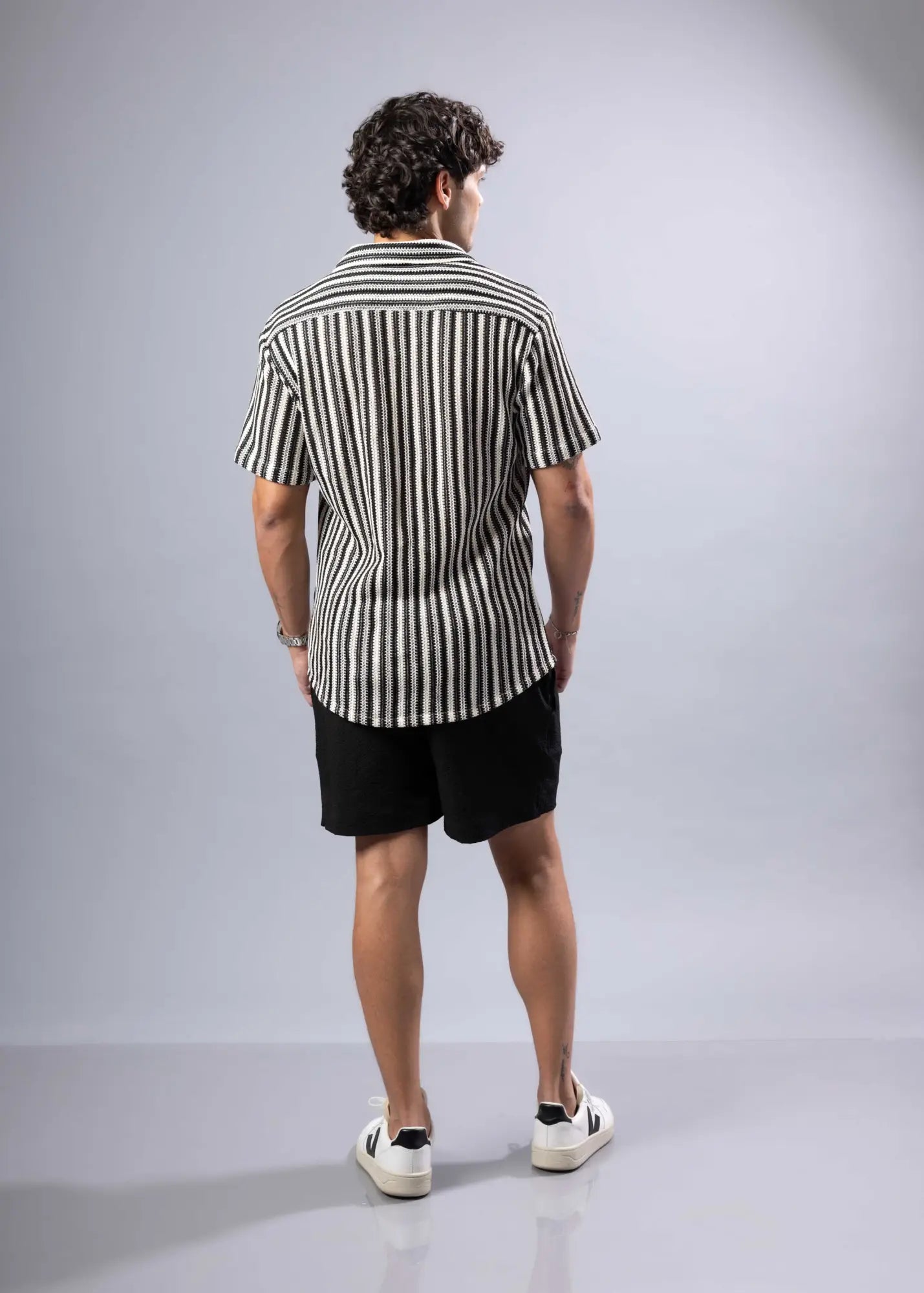 A man wearing a black and white vertically striped texture knit short-sleeved shirt in cotton blend fabric