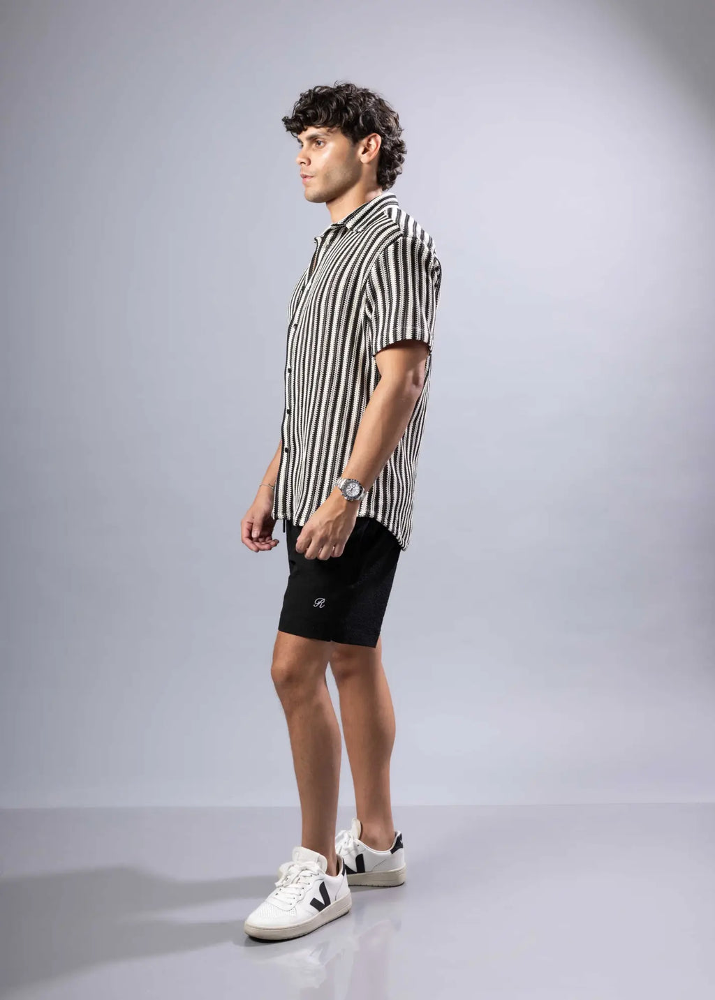 A man wearing a black and white vertically striped texture knit short-sleeved shirt in a casual style