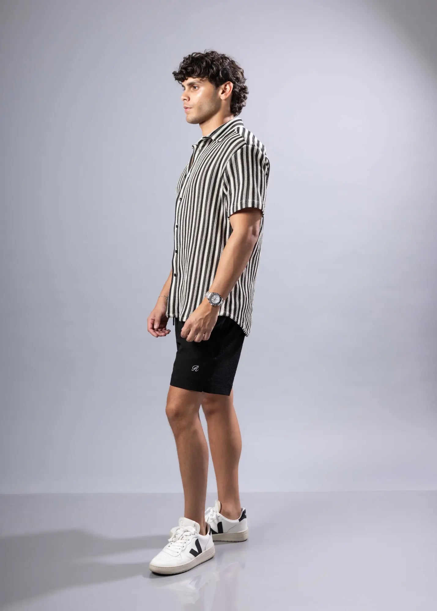 A man wearing a black and white vertically striped texture knit short-sleeved shirt in a casual style