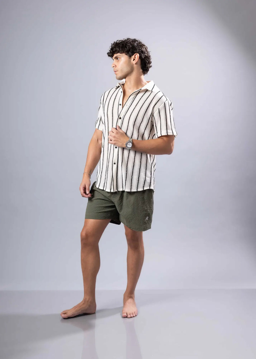 A man wearing a short-sleeved texture knit shirt with vertical black and white stripes