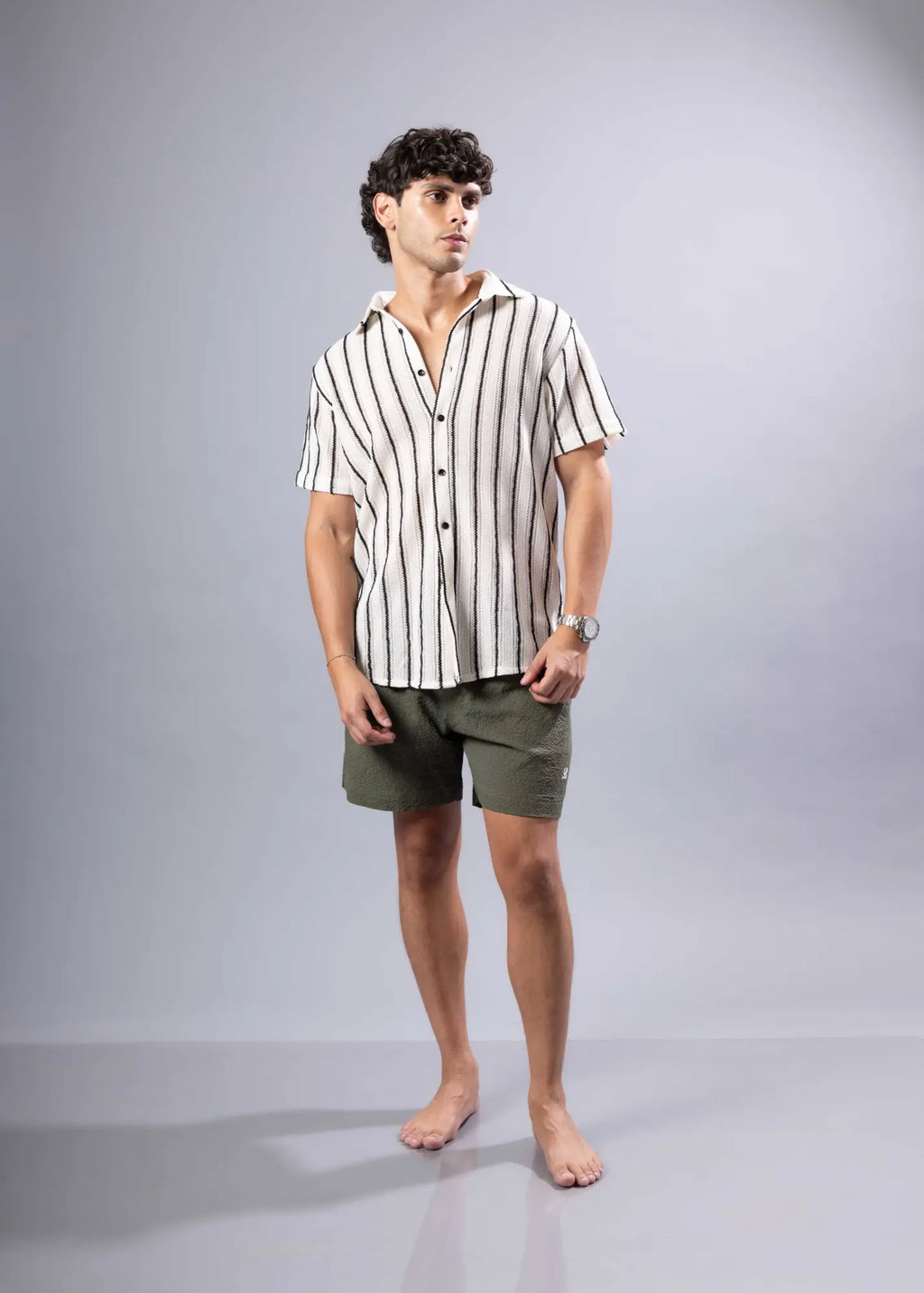 A man wearing a texture knit short-sleeved shirt with vertical black and off-white stripes
