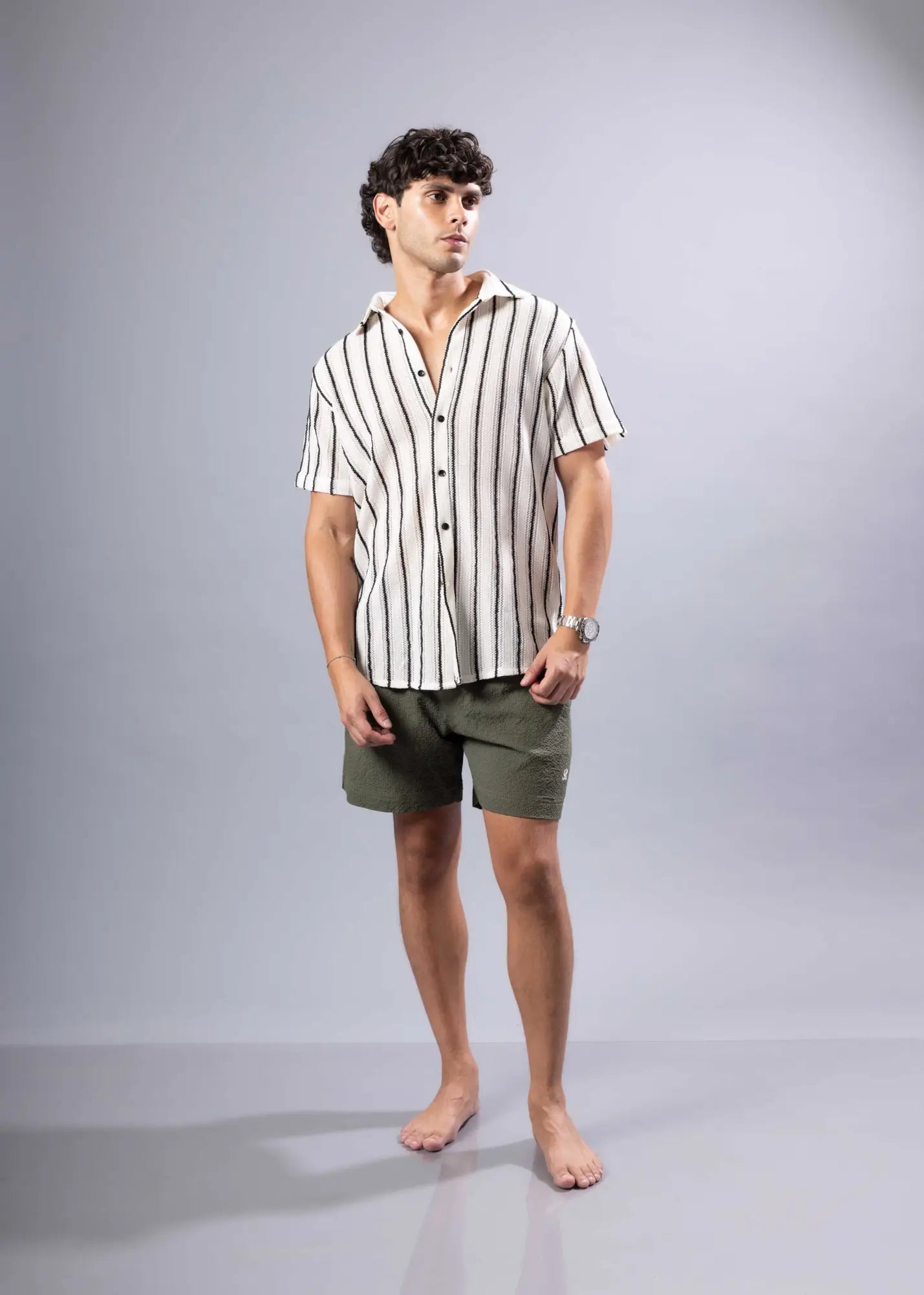 A man wearing a texture knit short-sleeved shirt with vertical black and off-white stripes