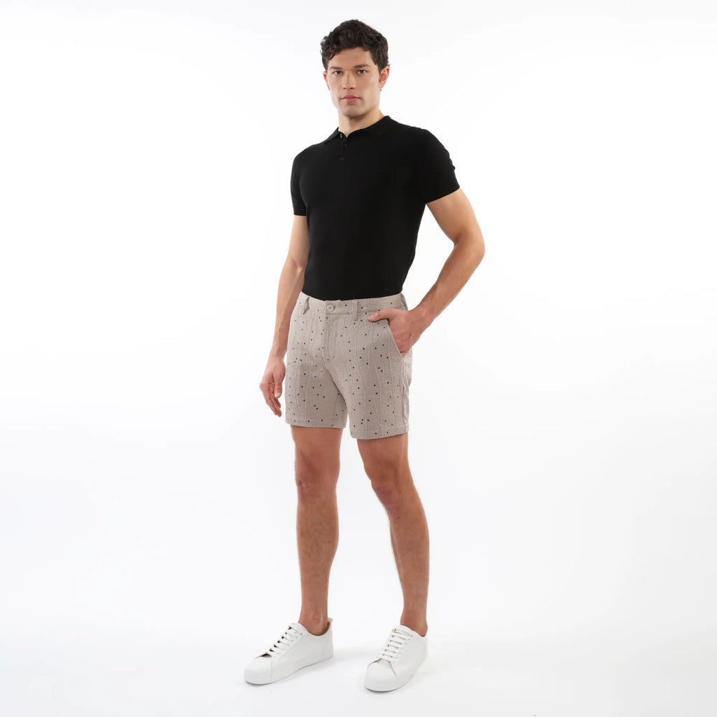 Beige textured jacquard stretch chino shorts with subtle dark dot pattern worn by model in casual summer attire