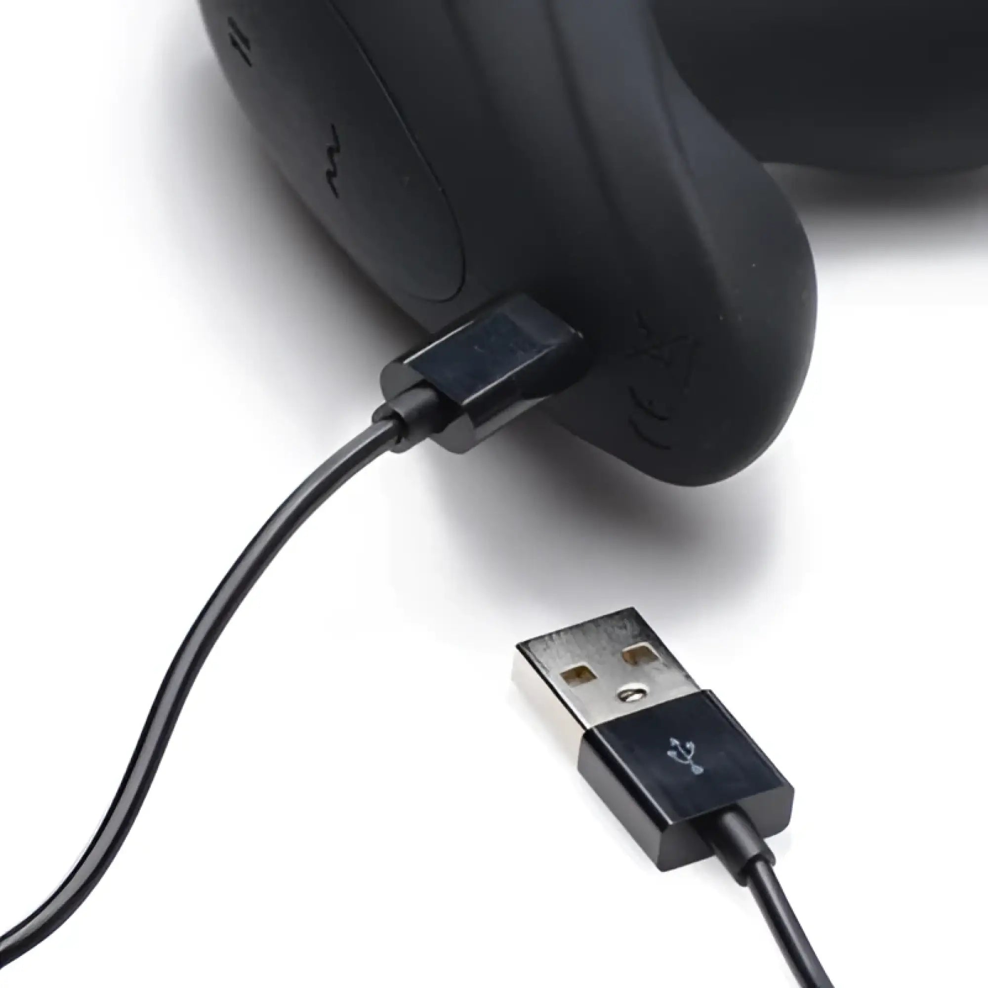 Thunderplugs black silicone anal plug being charged with a black USB magnetic charging cable against a white background.