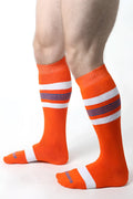 Bright orange tight end knee high socks with white and purple stripes featuring ribbed cuff and toe design